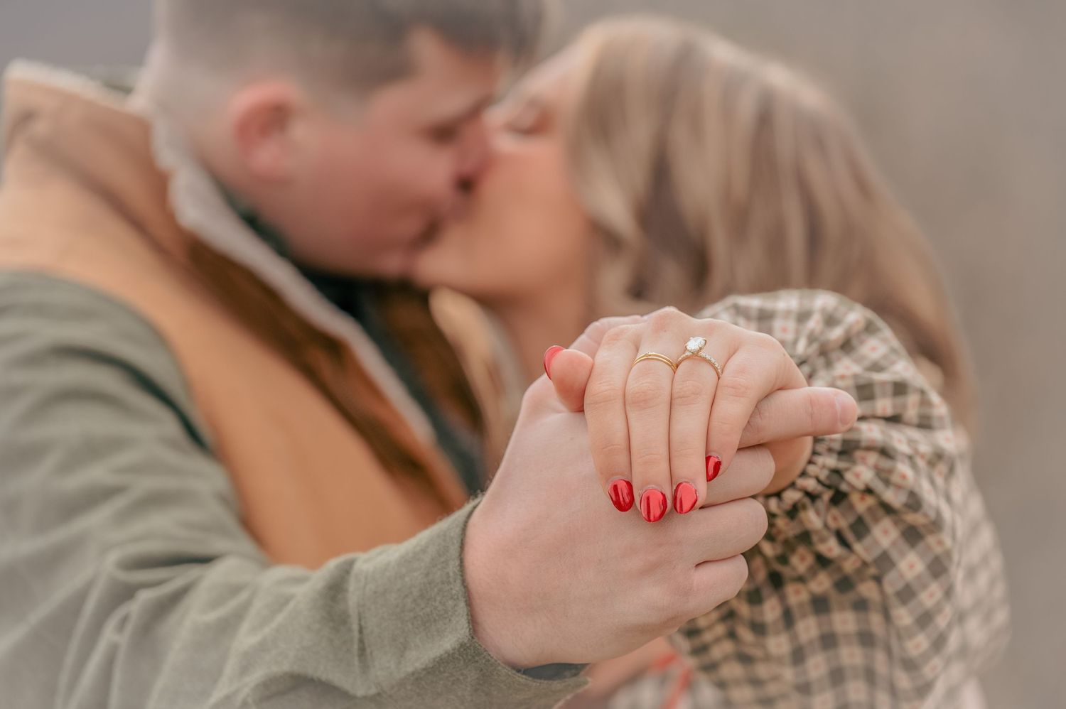 A romantic couple holding hands and sharing an intimate kiss, with bright red nail polish visible on clasped fingers in Gatlinburg TN.