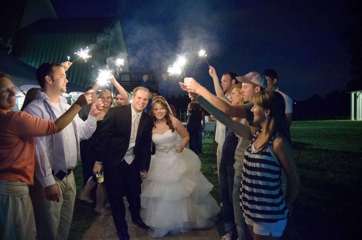 Wedding guests hold sparklers creating a magical nighttime pathway at an outdoor wedding reception in Sevierville TN.