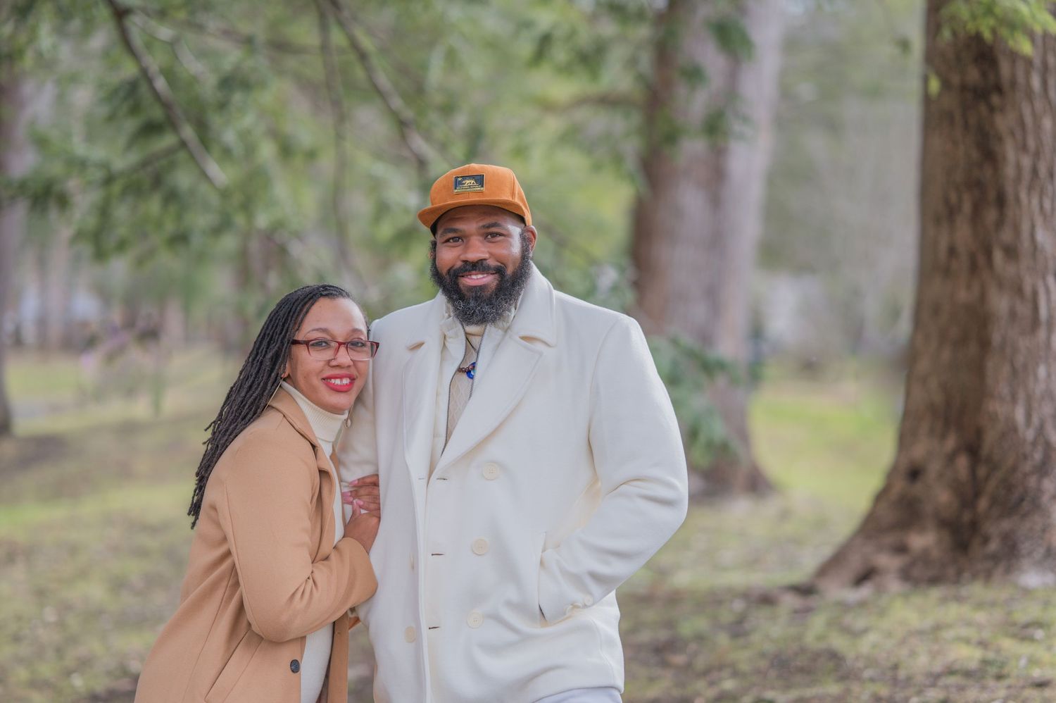 A couple shares a joyful moment together in a misty forest setting wearing neutral-colored coats by Townsend TN Photographers.