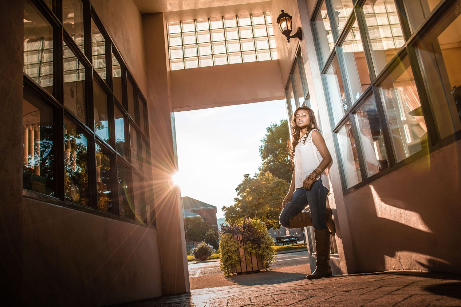 A figure hangs onto a tall pole outside a modern building at sunset, creating a dramatic silhouette against the golden light.