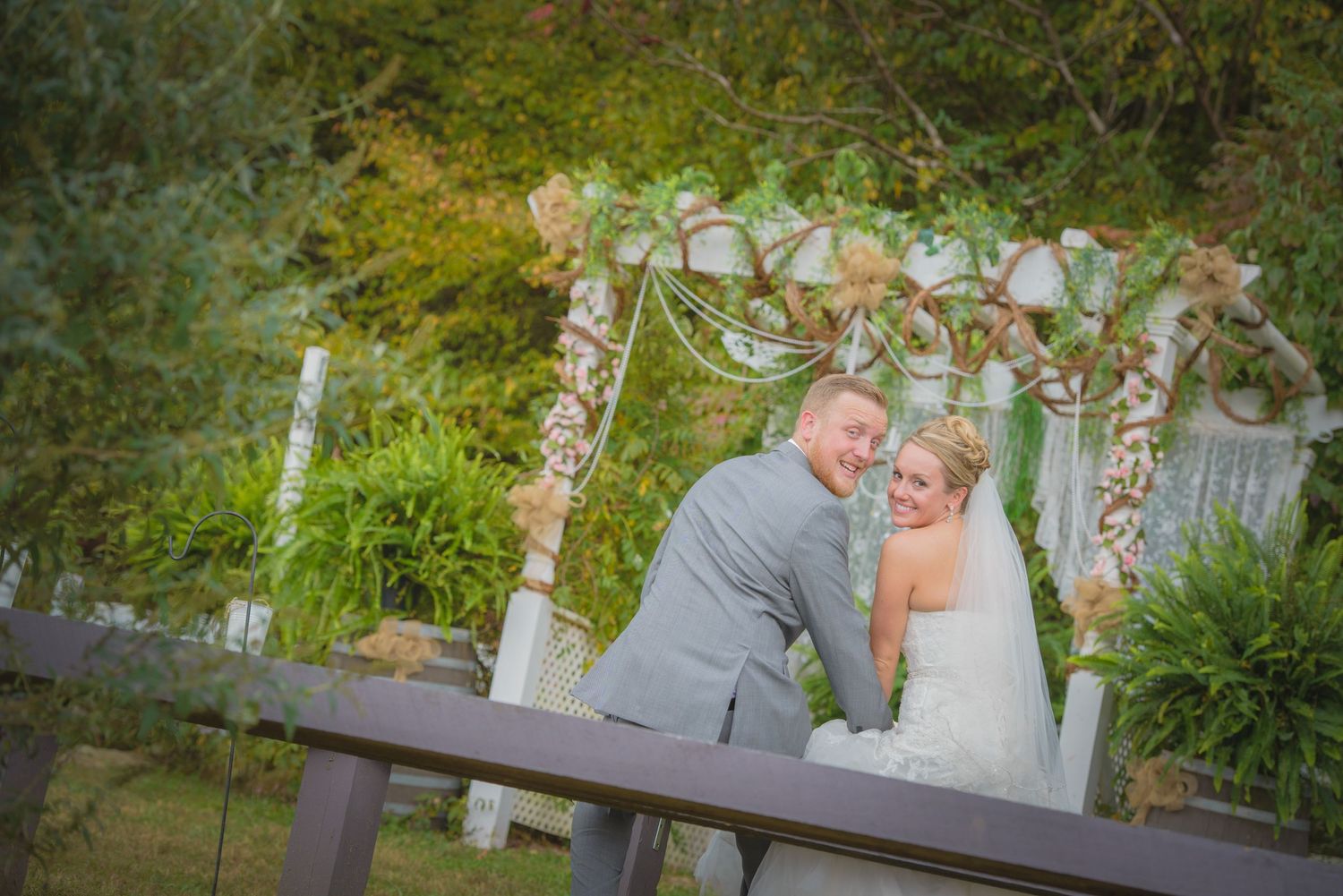 A couple celebrates their wedding day under an elegant floral arch in a lush garden setting in Townsend TN.
