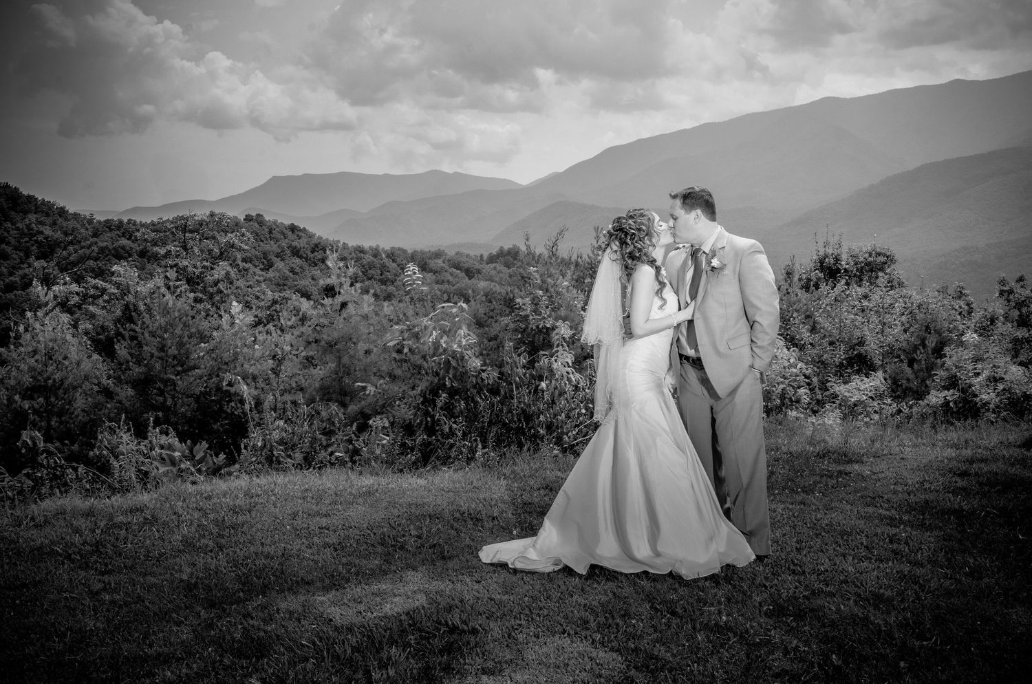 Black and white romantic outdoor wedding photo of couple embracing on mountainside with scenic natural backdrop in Pigeon Forge TN.