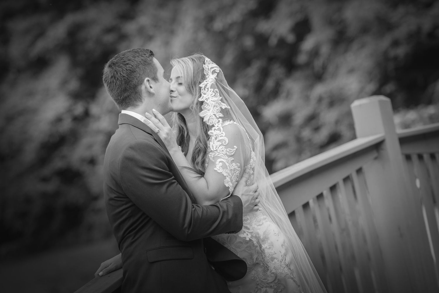 A tender black and white wedding moment captured on a wooden deck with soft bokeh background by Pigeon Forge Photographers.