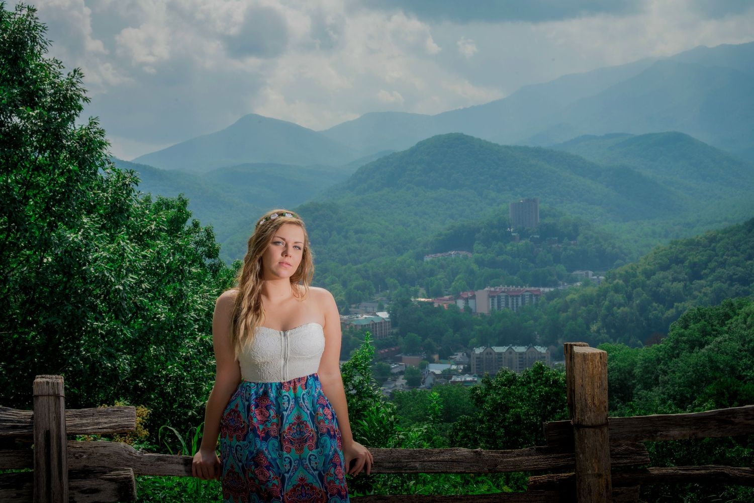 A scenic mountain overlook in Western North Carolina showcases rolling green peaks and a distant resort under blue skies.