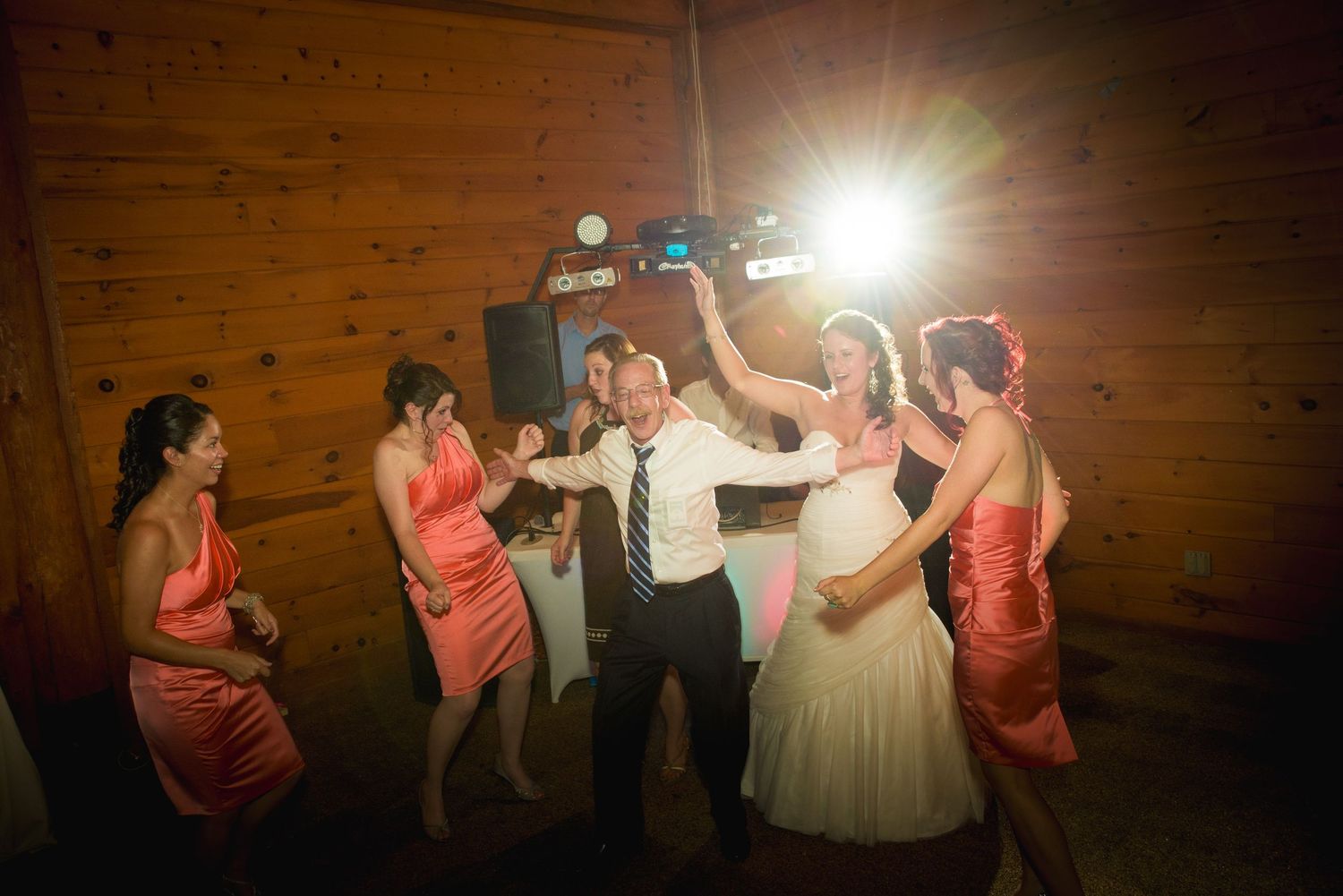 Joyful wedding party dancing and celebrating in a rustic wooden barn venue with bright lighting in Gatlinburg TN.