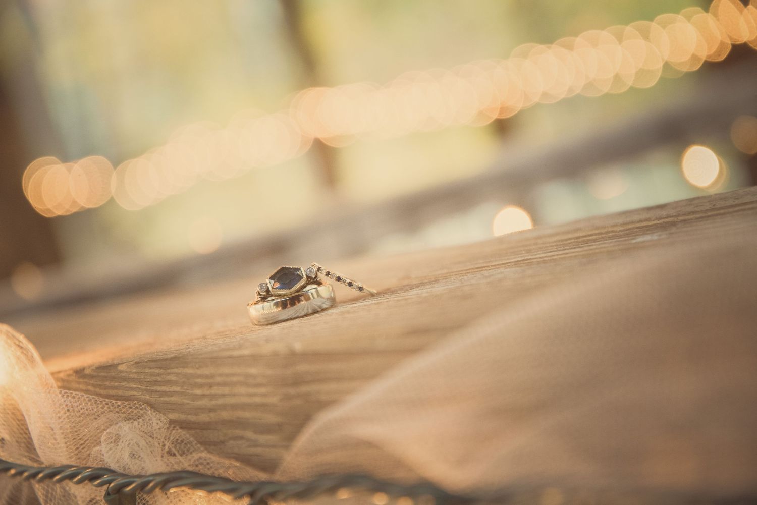 Wedding rings rest on a textured surface with soft bokeh lights creating a romantic ambiance in the background by Gatlinburg TN Weddings.