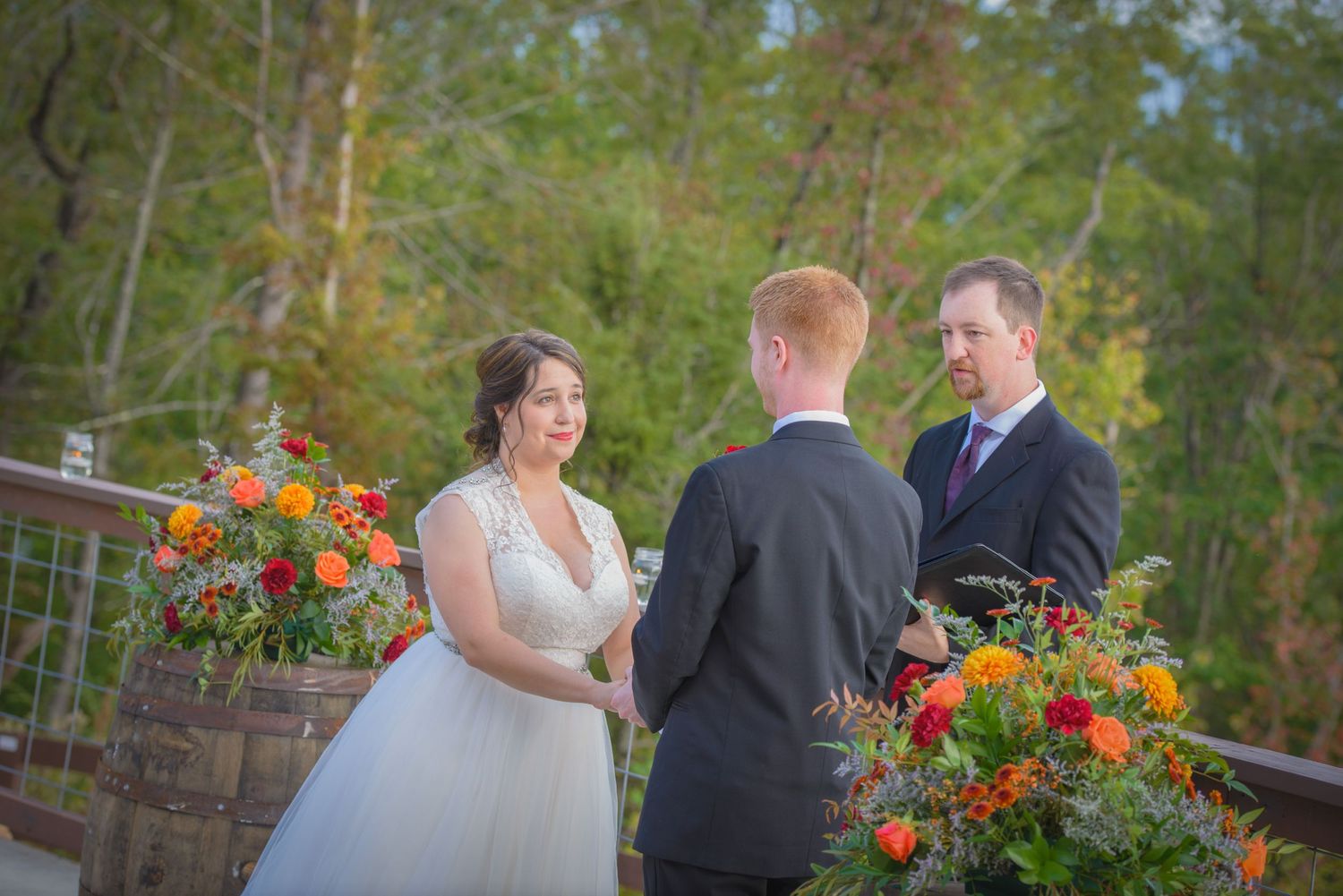 An outdoor autumn wedding ceremony with vibrant orange flowers decorating a rustic wooden altar in a forest setting in Pigeon Forge TN.