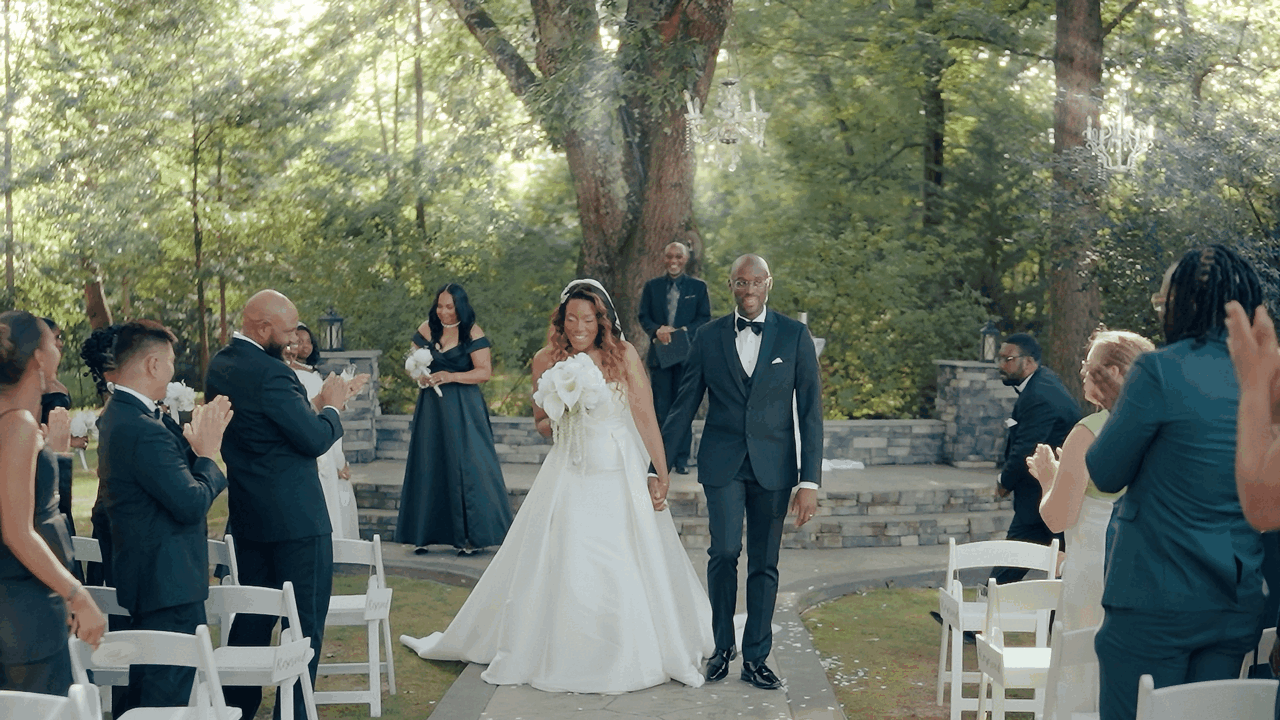 Outdoor wedding ceremony in wooded area with white chairs and natural decor.