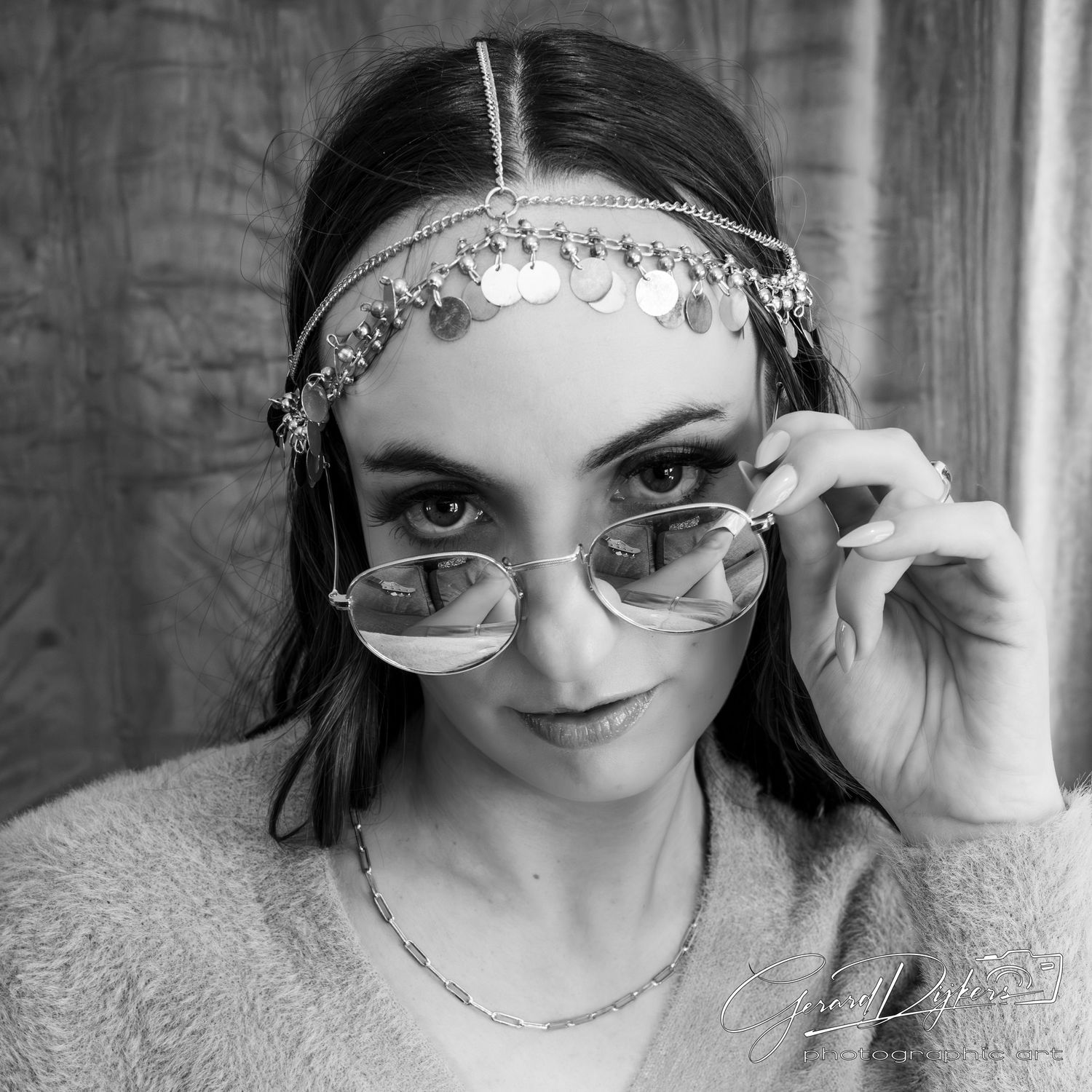 A person wearing ornate headpiece jewelry and sunglasses poses in a black and white photo series.