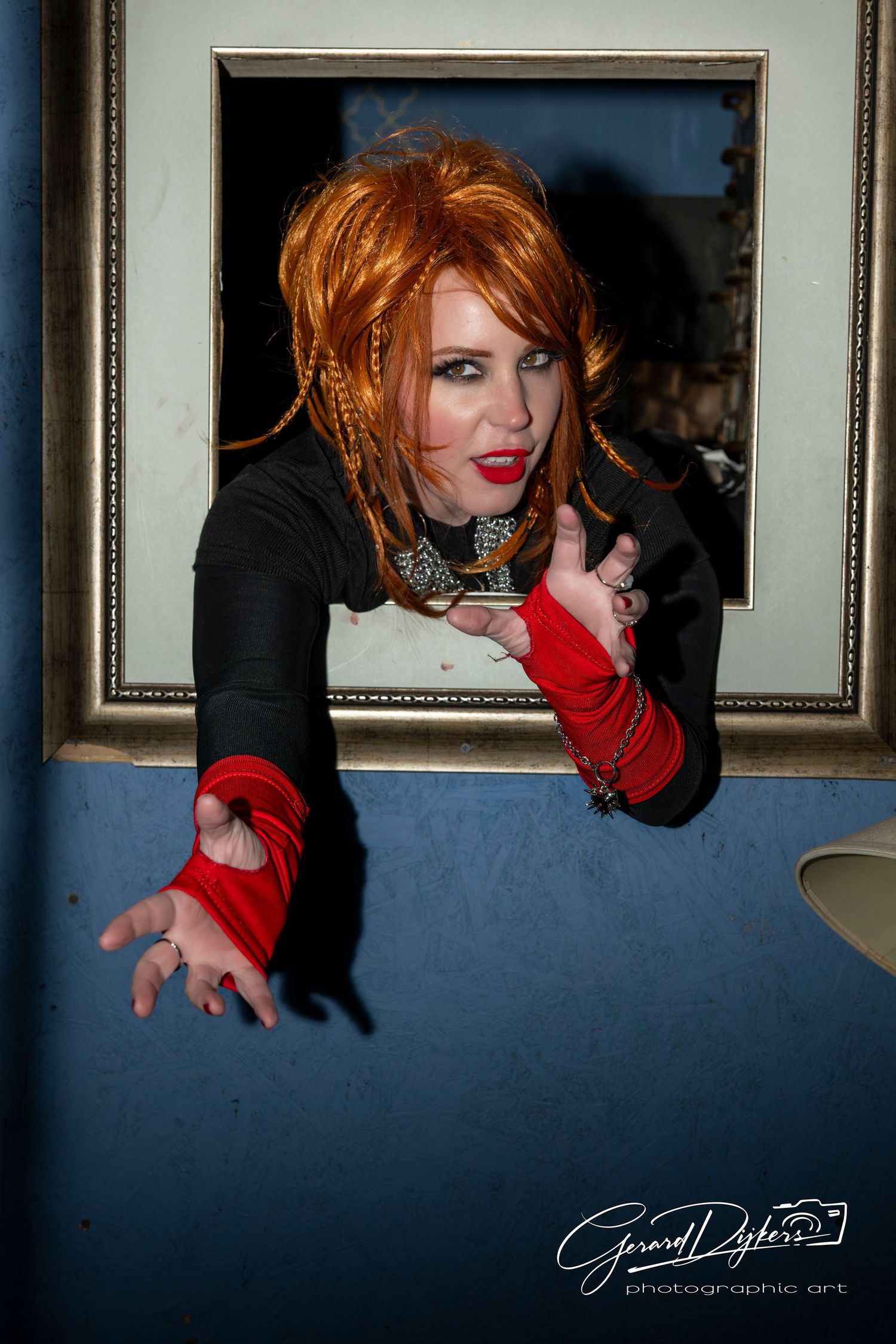 Artistic photo series showing a person in red gloves reaching dramatically against a dark blue wall with framed artwork.