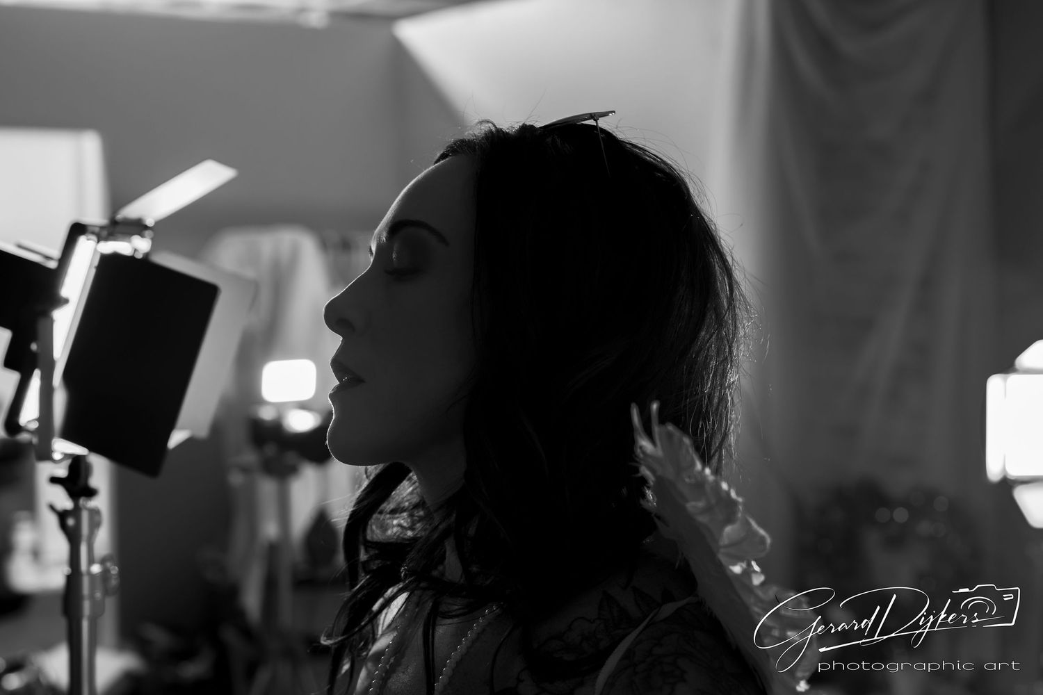 Black and white photo of a person singing into a microphone in a recording studio setting.
