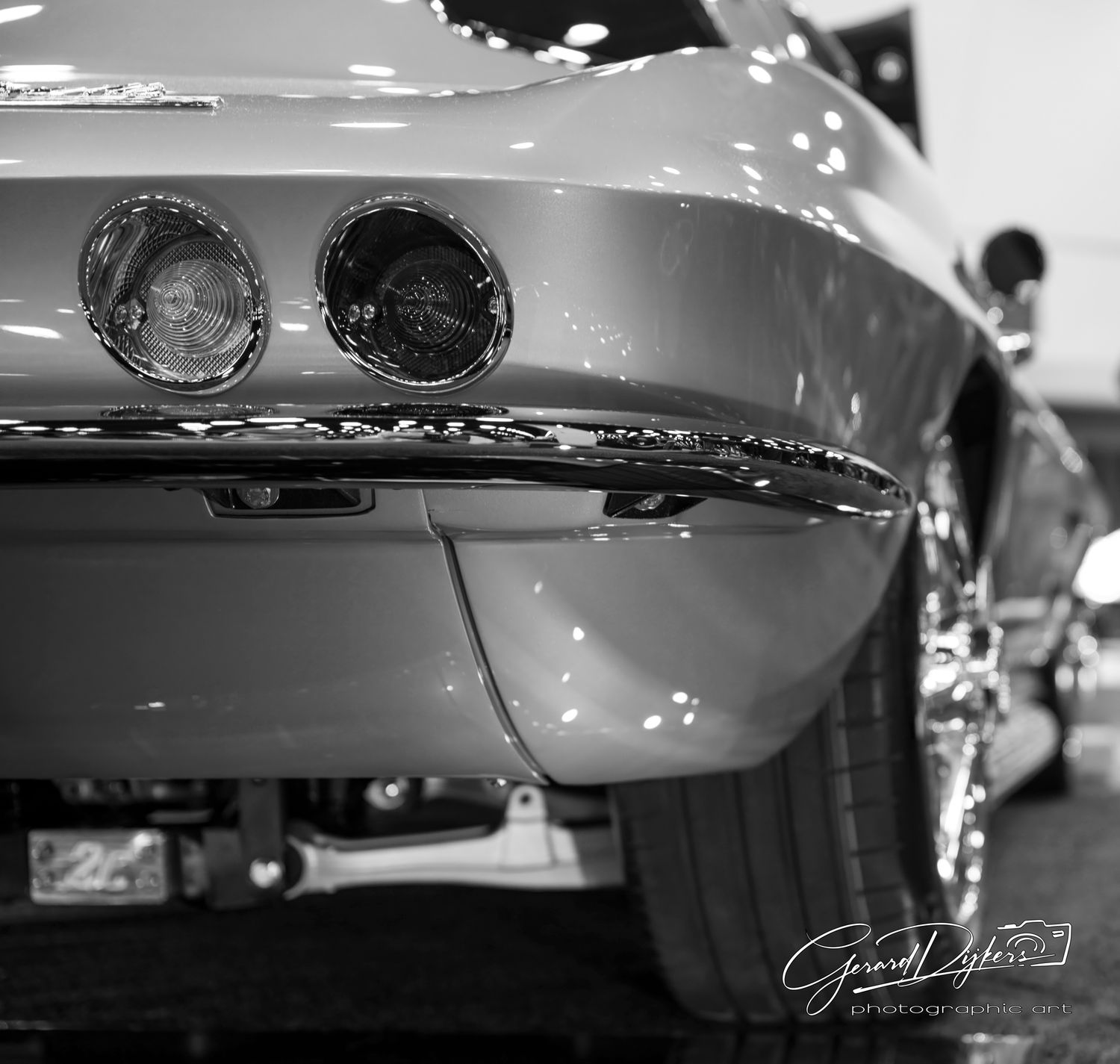 Close-up black and white photograph showing details of classic car headlights and chrome trim.