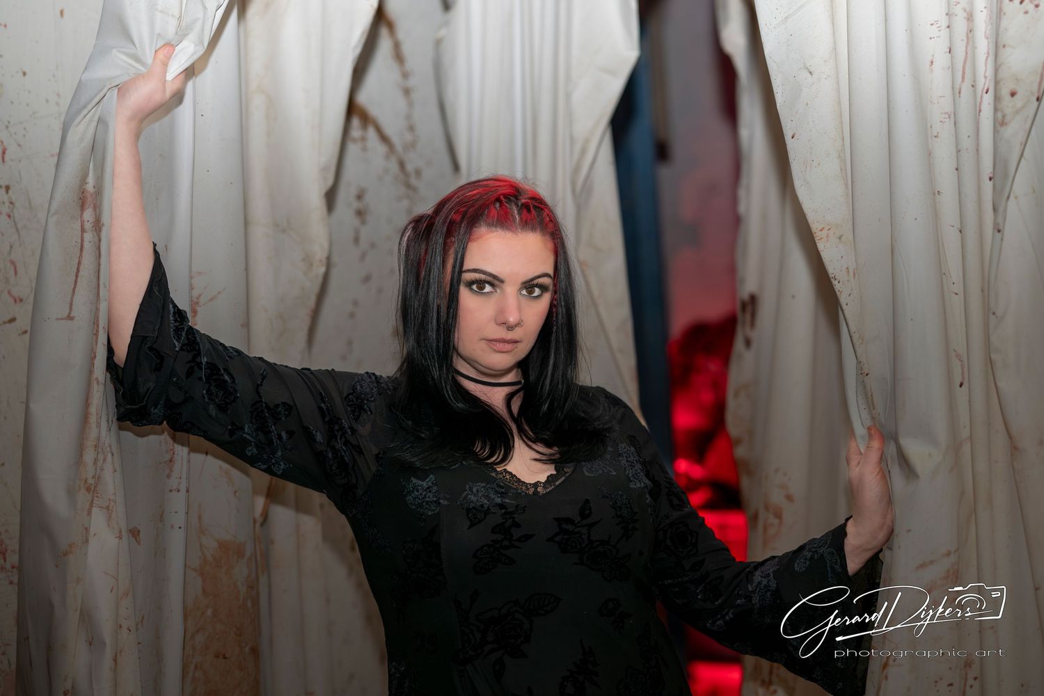 A person dances expressively in front of a white curtain backdrop with dramatic red lighting effects.