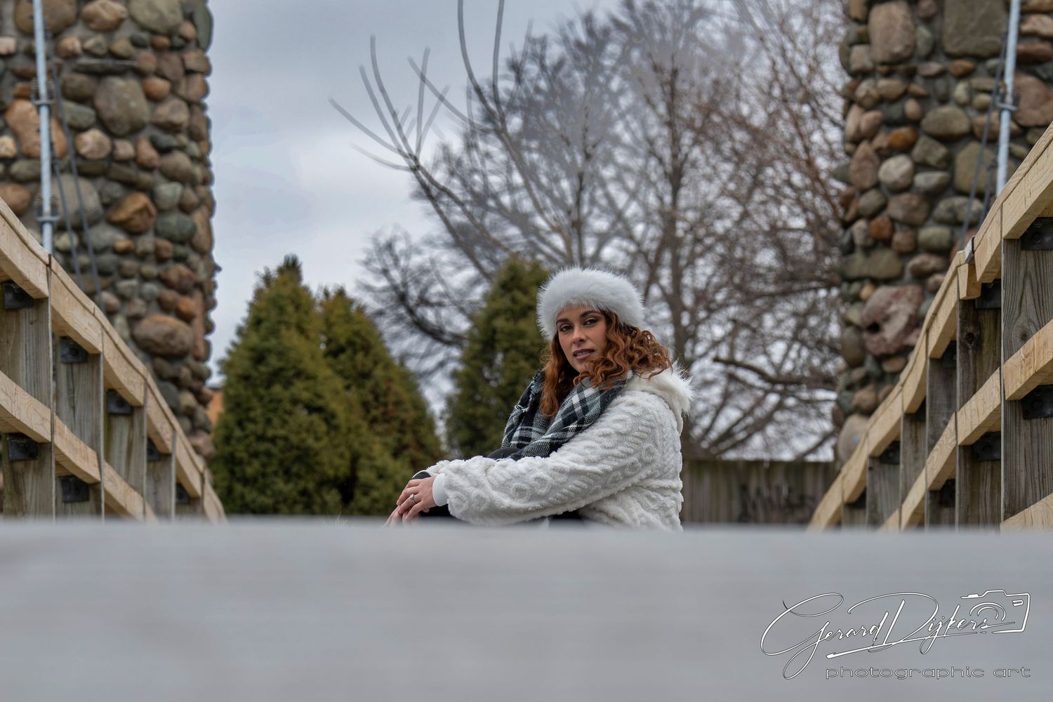 A person in a gray hoodie performs a parkour jump between stone pillars on a winter day.