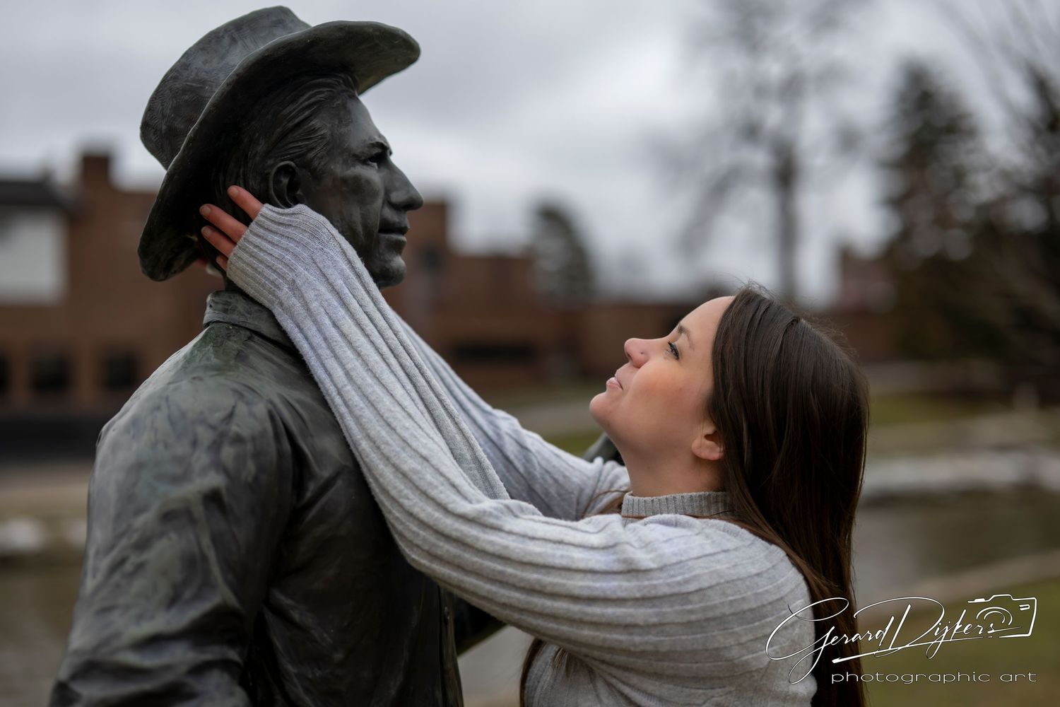 A couple in winter coats embraces in a romantic moment outdoors during a cloudy day.