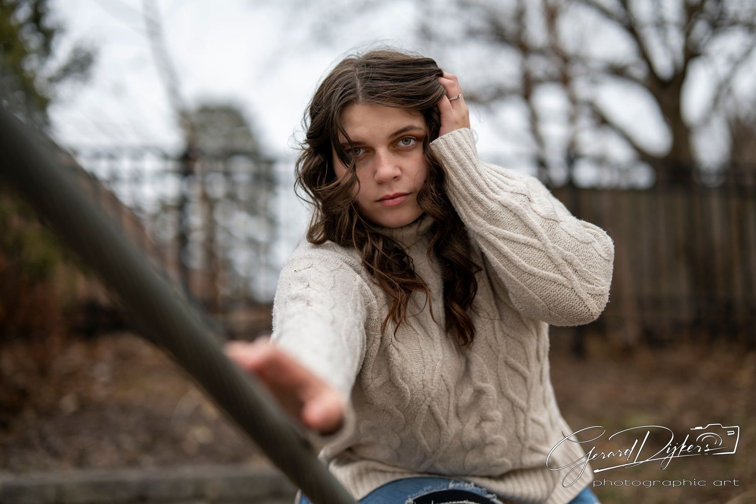 A person in a cream knit sweater poses outdoors against a blurred winter background.