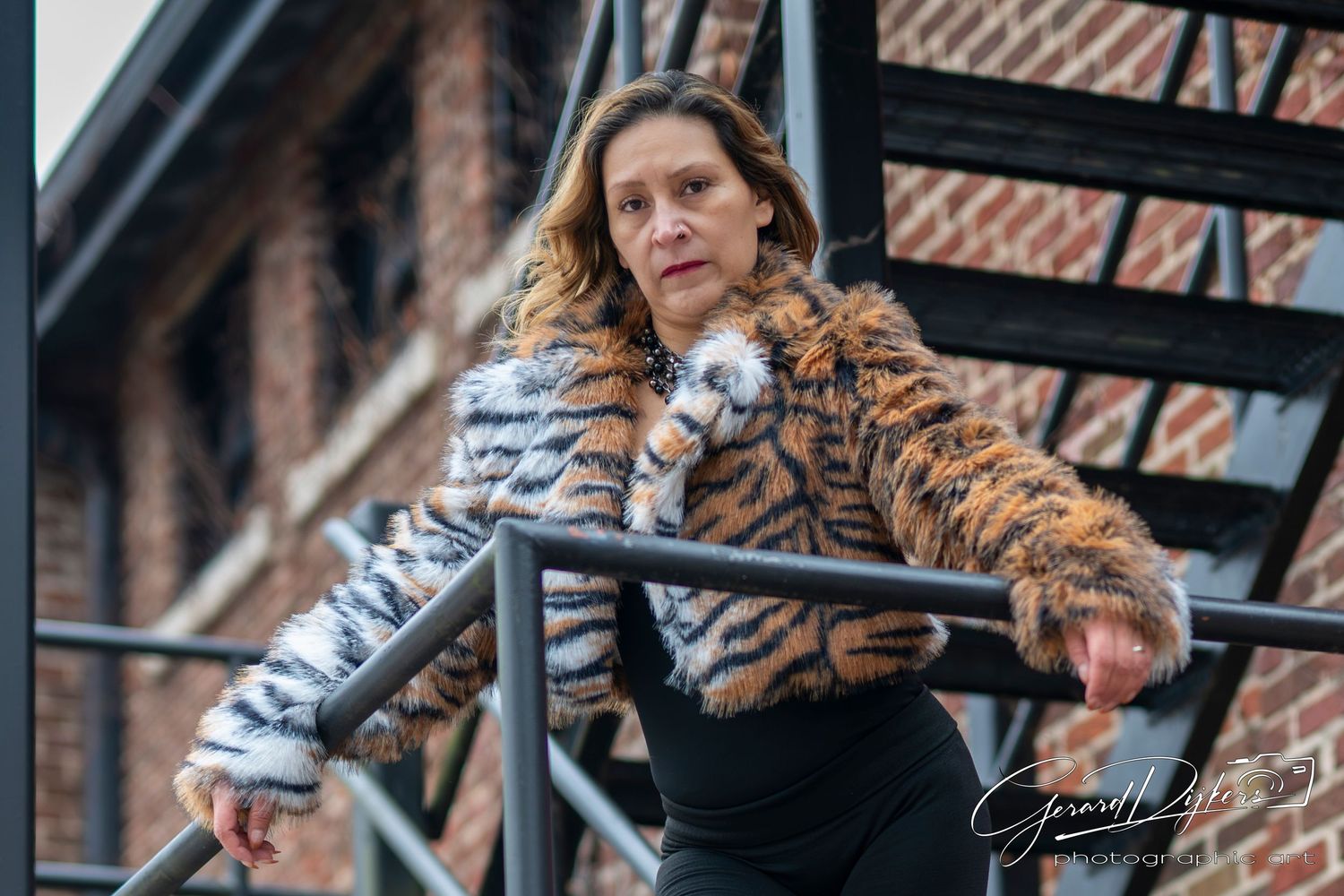Person in animal print fur coat stands near industrial metal structures in urban setting.