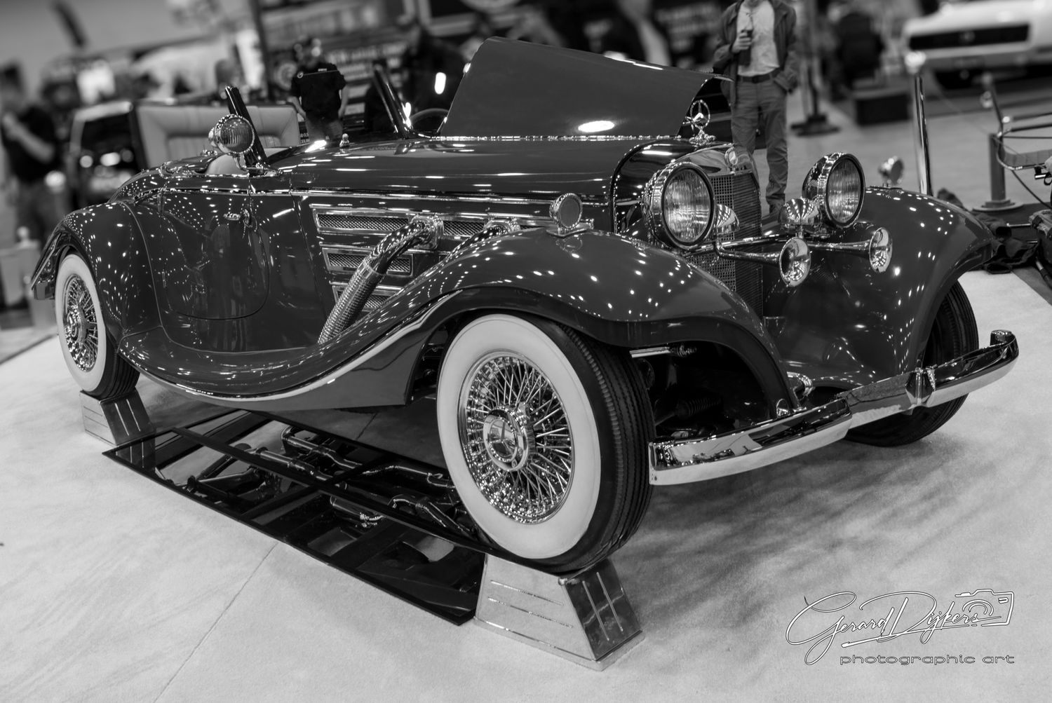 Classic vintage Mercedes-Benz 500K convertible in black and white displayed at an auto show.