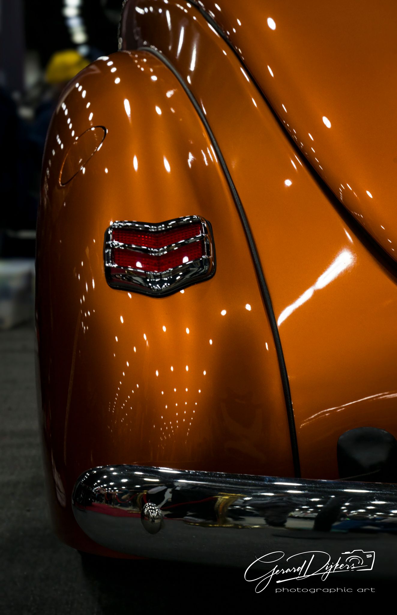 Close-up sequence of a glossy orange car hood with chrome trim reflecting light in a dramatic studio setting.