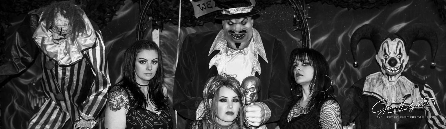 Black and white photo of a gothic metal band posing together in dramatic dark costumes and makeup.