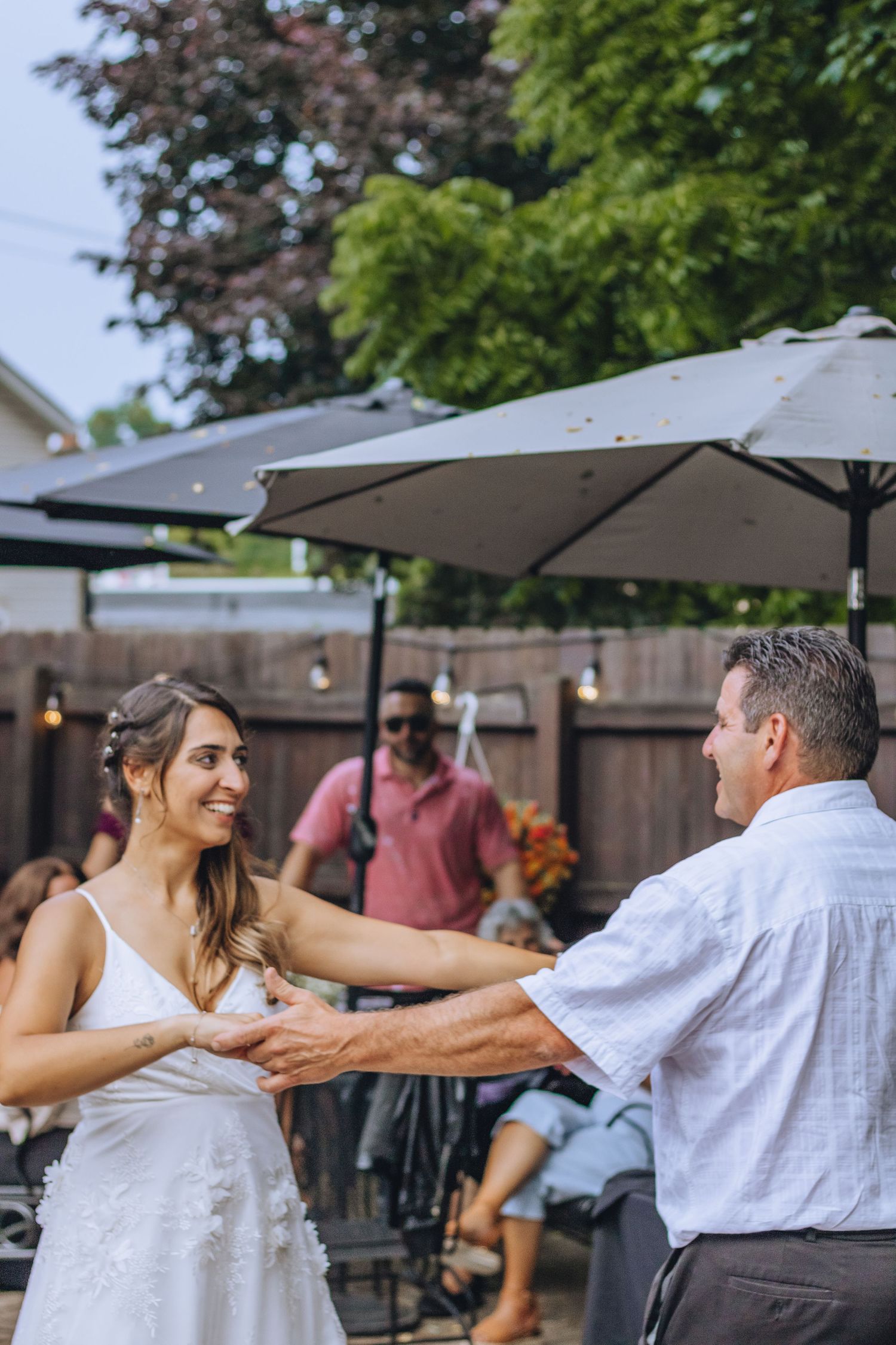 A casual outdoor celebration under patio umbrellas with people dancing on a summer evening.