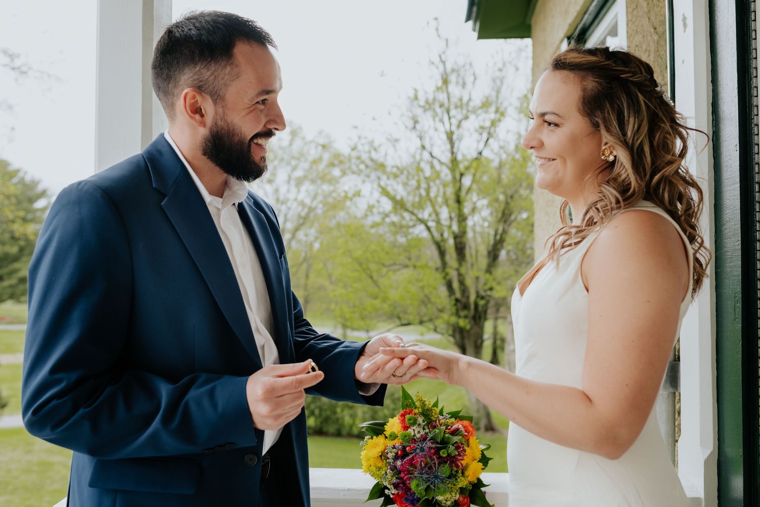 A couple shares an intimate moment outdoors during their wedding ceremony with natural greenery in the background.
