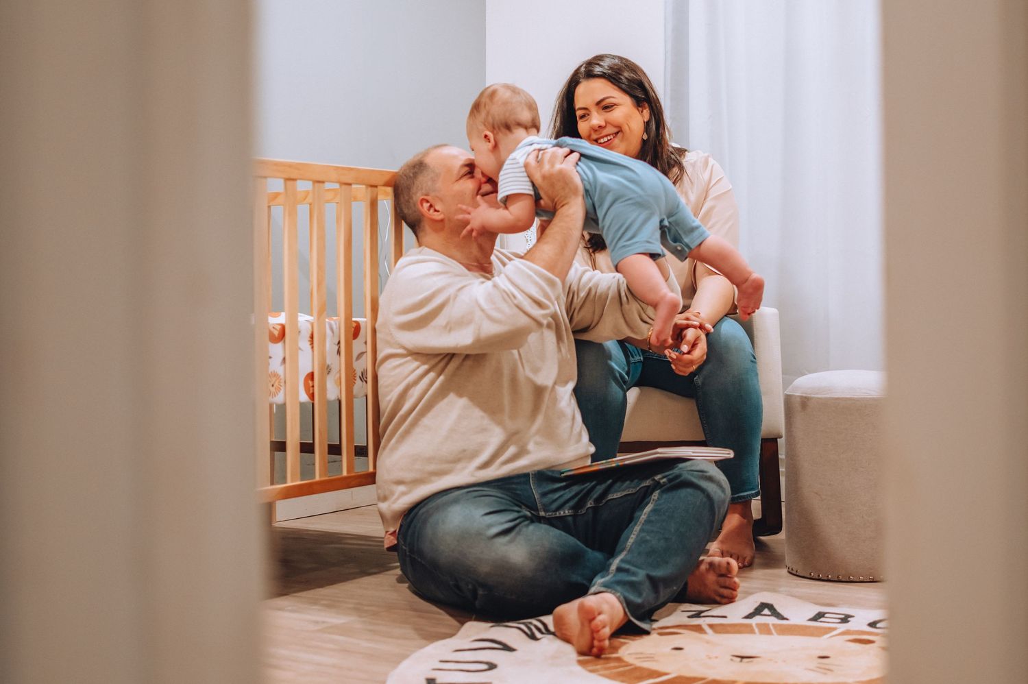 Joyful family moment captured in a nursery with a decorative round rug and wooden crib.