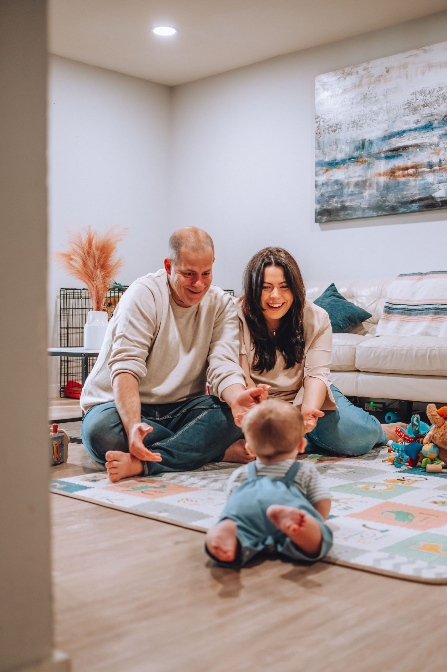 Family enjoying playtime together on colorful alphabet mat in cozy living room setting.