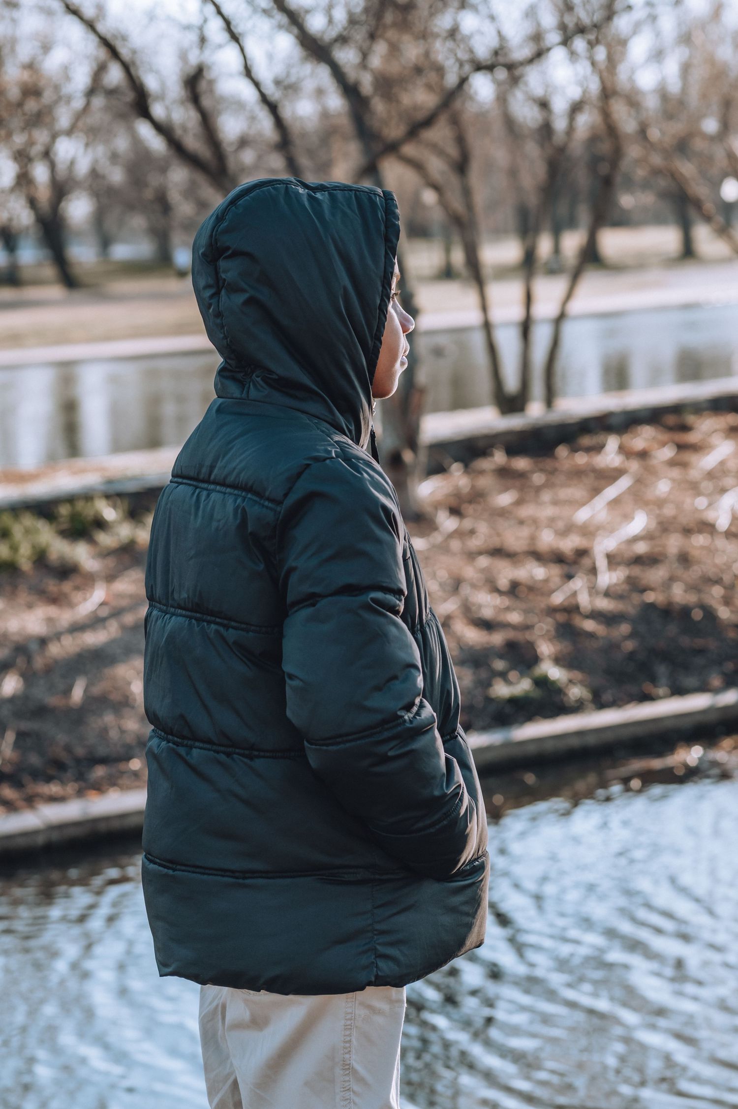 Person in dark puffy winter coat looks out over water.