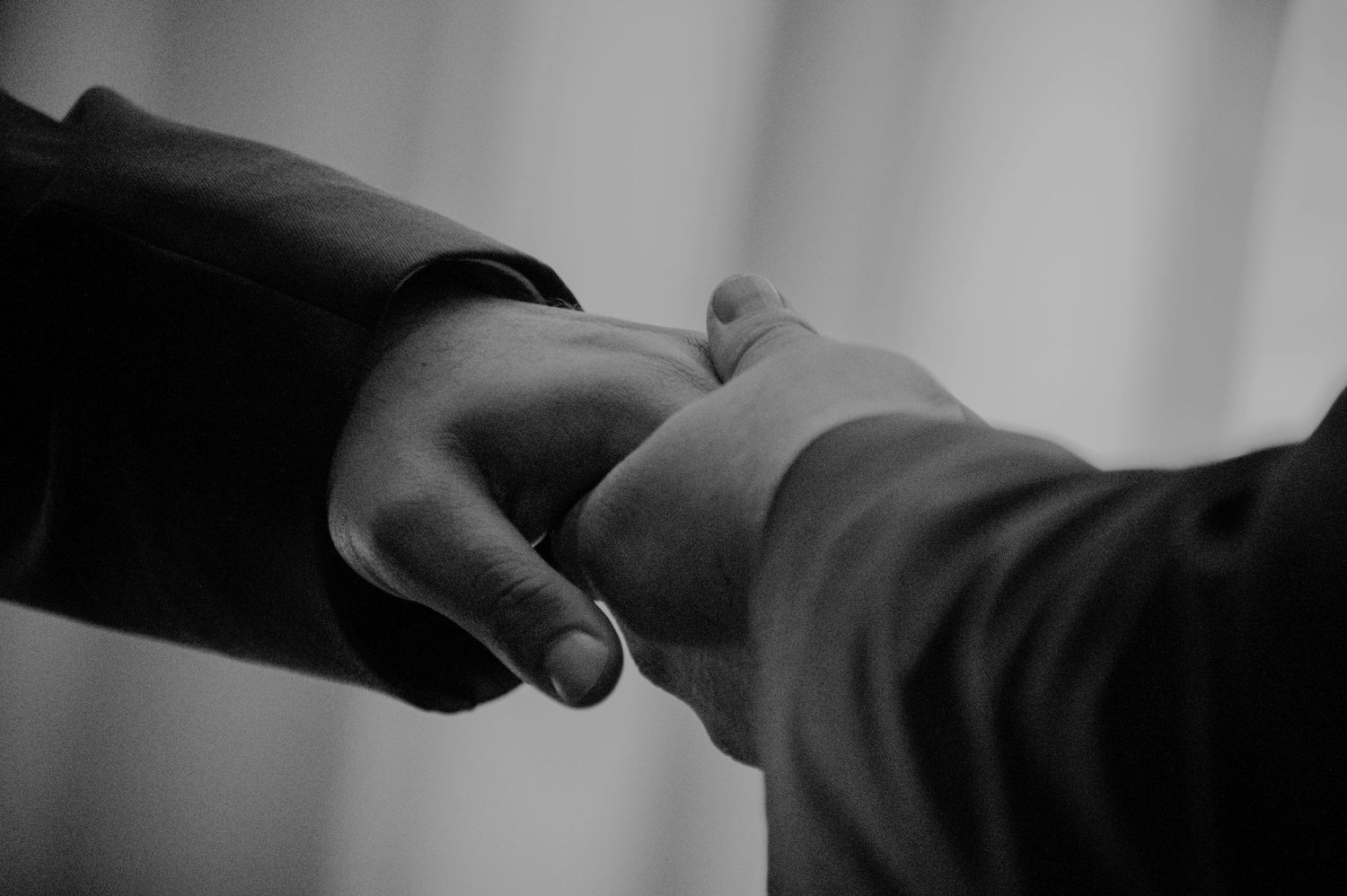 Two hands reaching out to touch fingertips in a gentle, intimate black and white gesture.