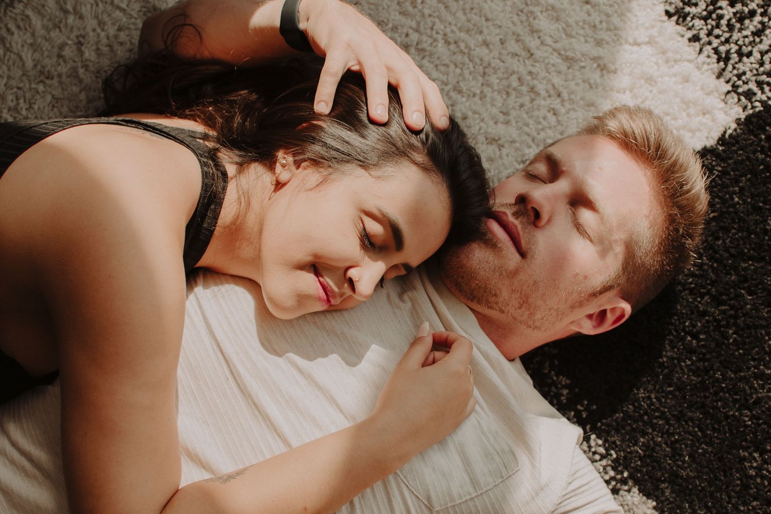 A romantic couple lying together on a blanket outdoors expressing affection and tenderness in black and white tones.