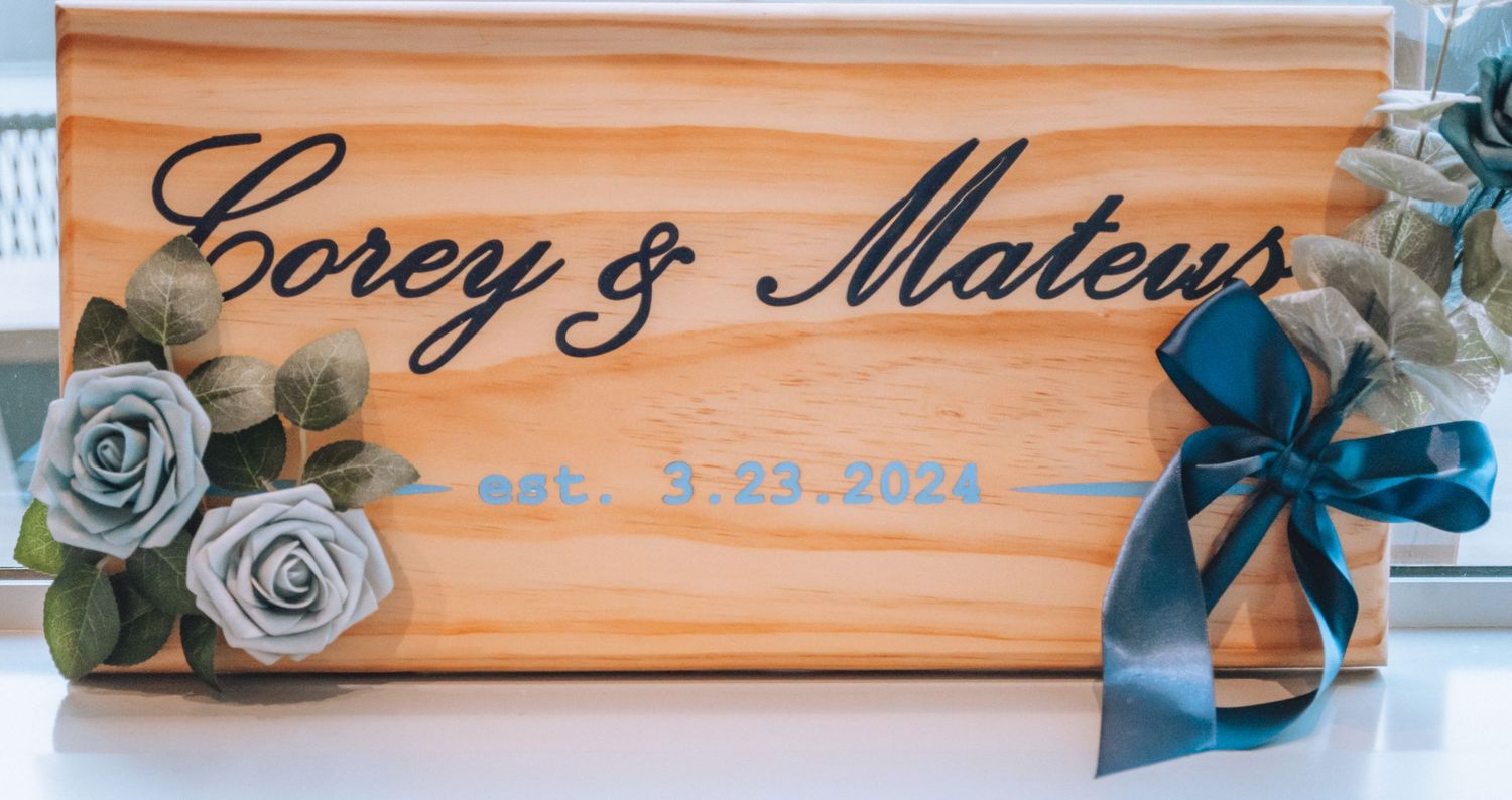 Personalized wooden sign with decorative blue roses on both ends shows elegant cursive text engraved on cedar plank.