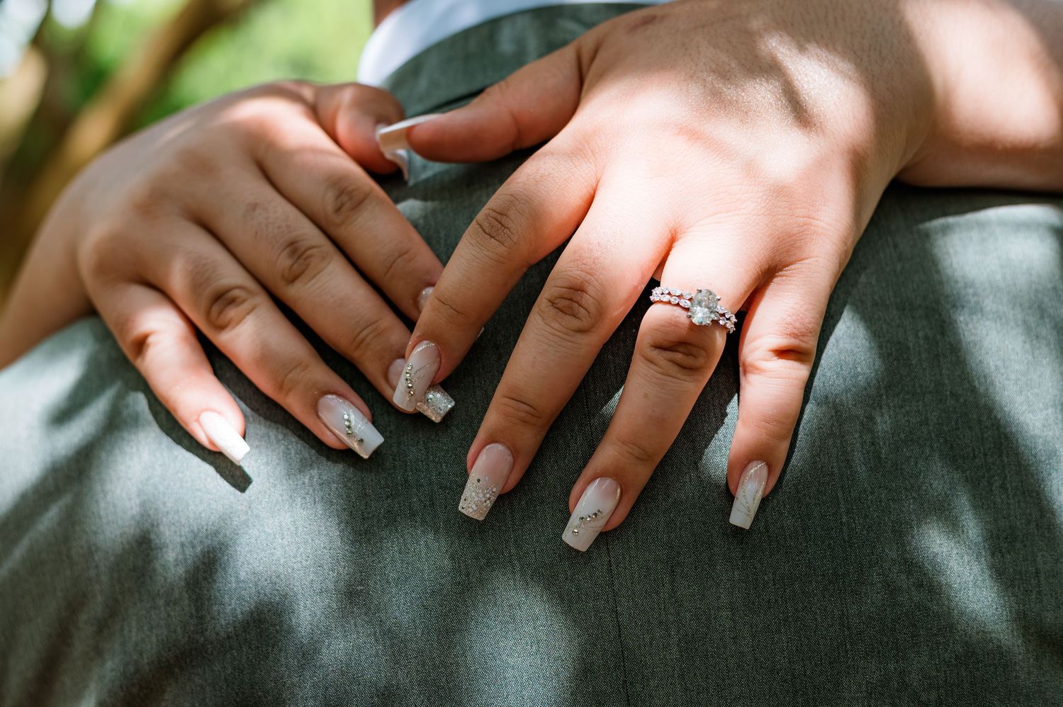Close-up shots of hands wearing wedding rings against a grey textured fabric background.