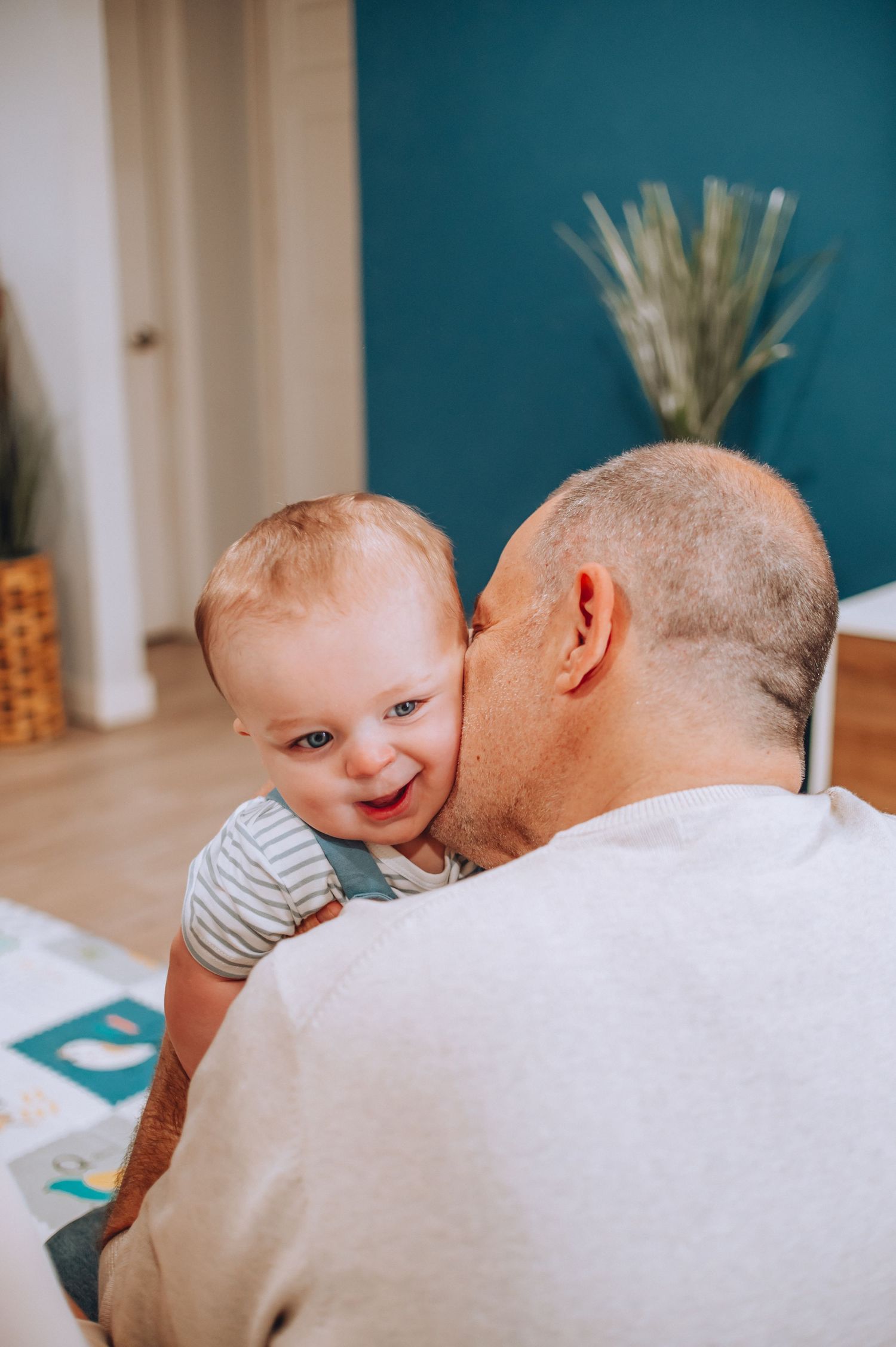 Tender moment shared between baby in striped shirt and adult during playtime.