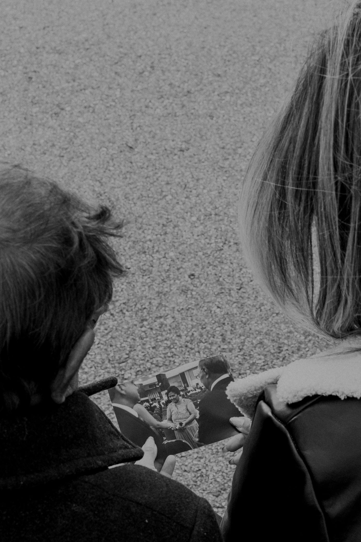 Black and white image of two people looking at a phone screen together.