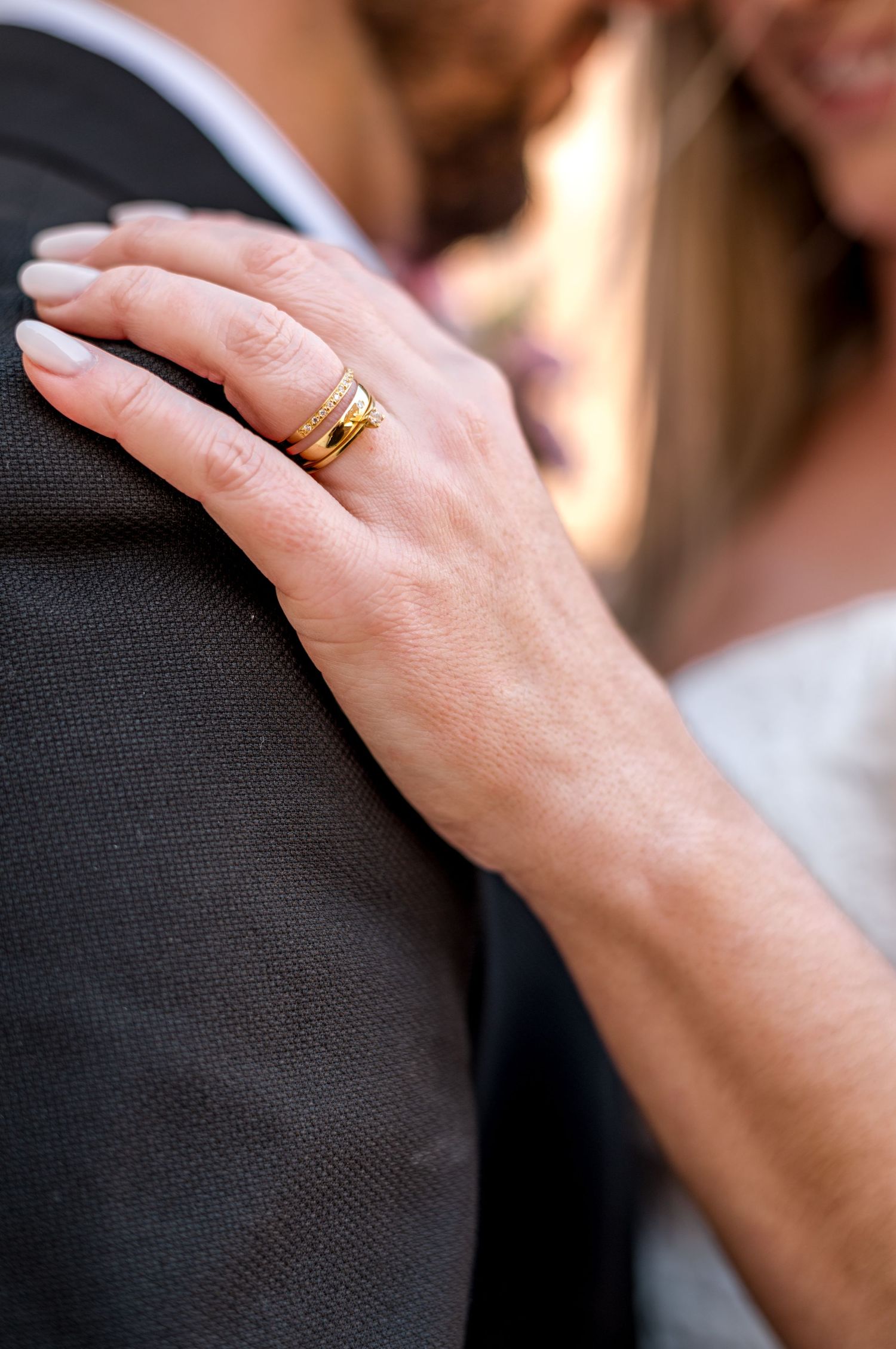 A close-up of a wedding ring on display as a hand rests on formal attire.