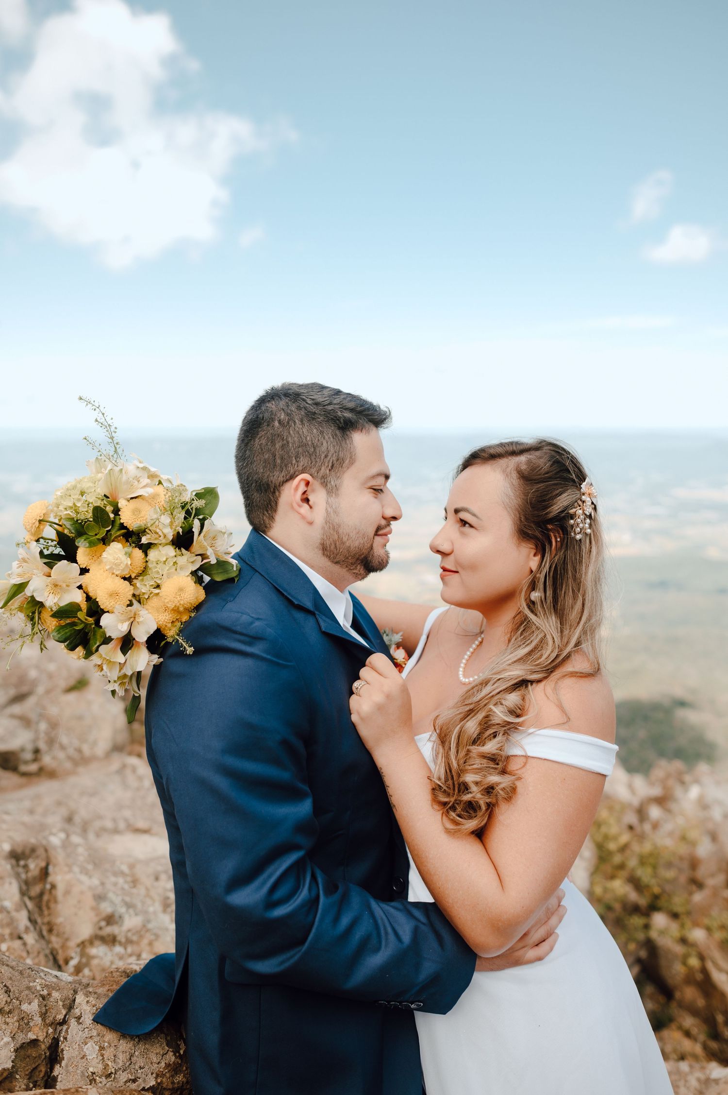 A romantic wedding couple shares an intimate moment against a scenic mountain backdrop on their special day.