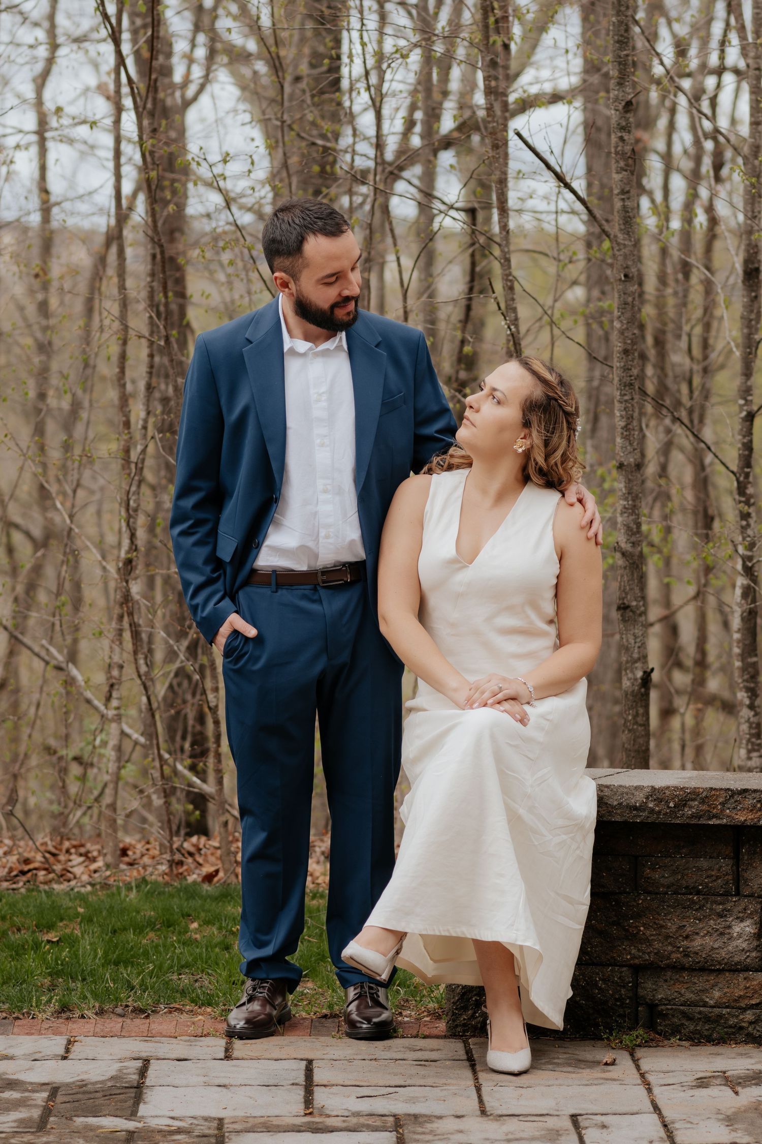 Bride and groom share sweet moments together on stone steps during an outdoor spring forest wedding photoshoot.