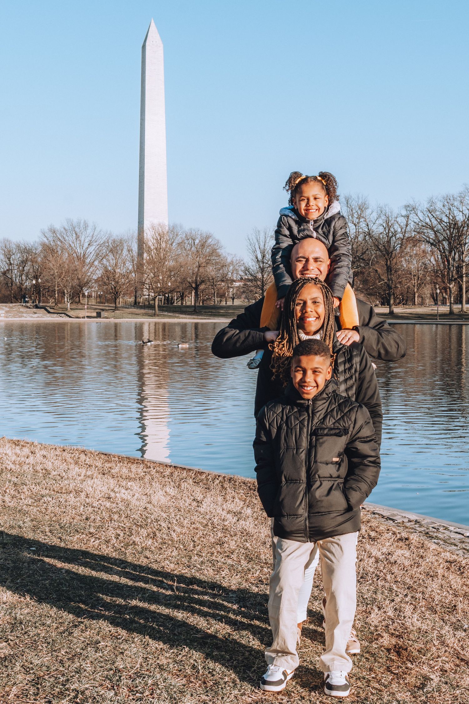 A group poses together by the Washington Monument reflecting pool on a sunny day.