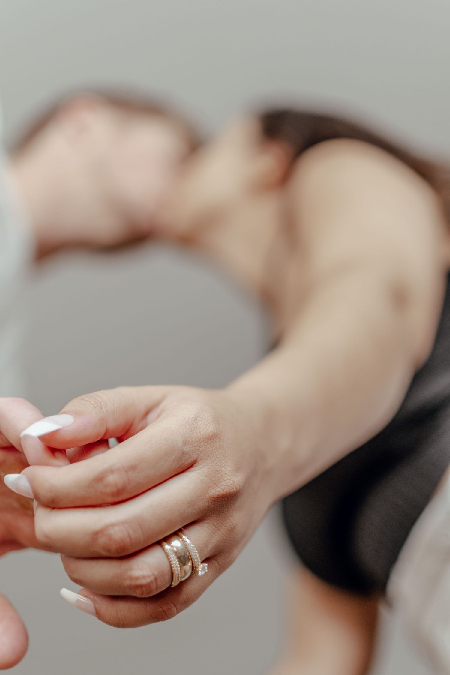 Close-up view of hands wearing wedding rings during an intimate dance moment.