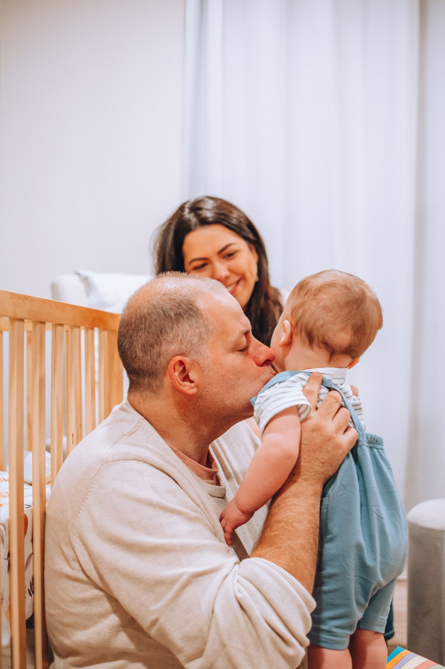 Tender moment shared between family members in a minimalist nursery setting.