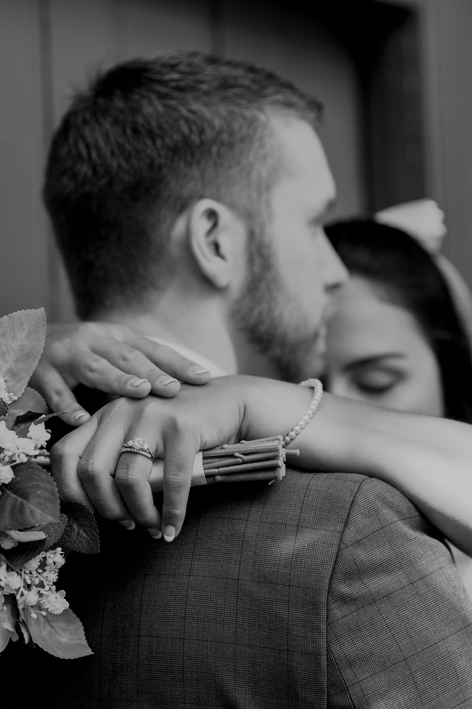Black and white intimate wedding photo showing close embrace and wedding rings.