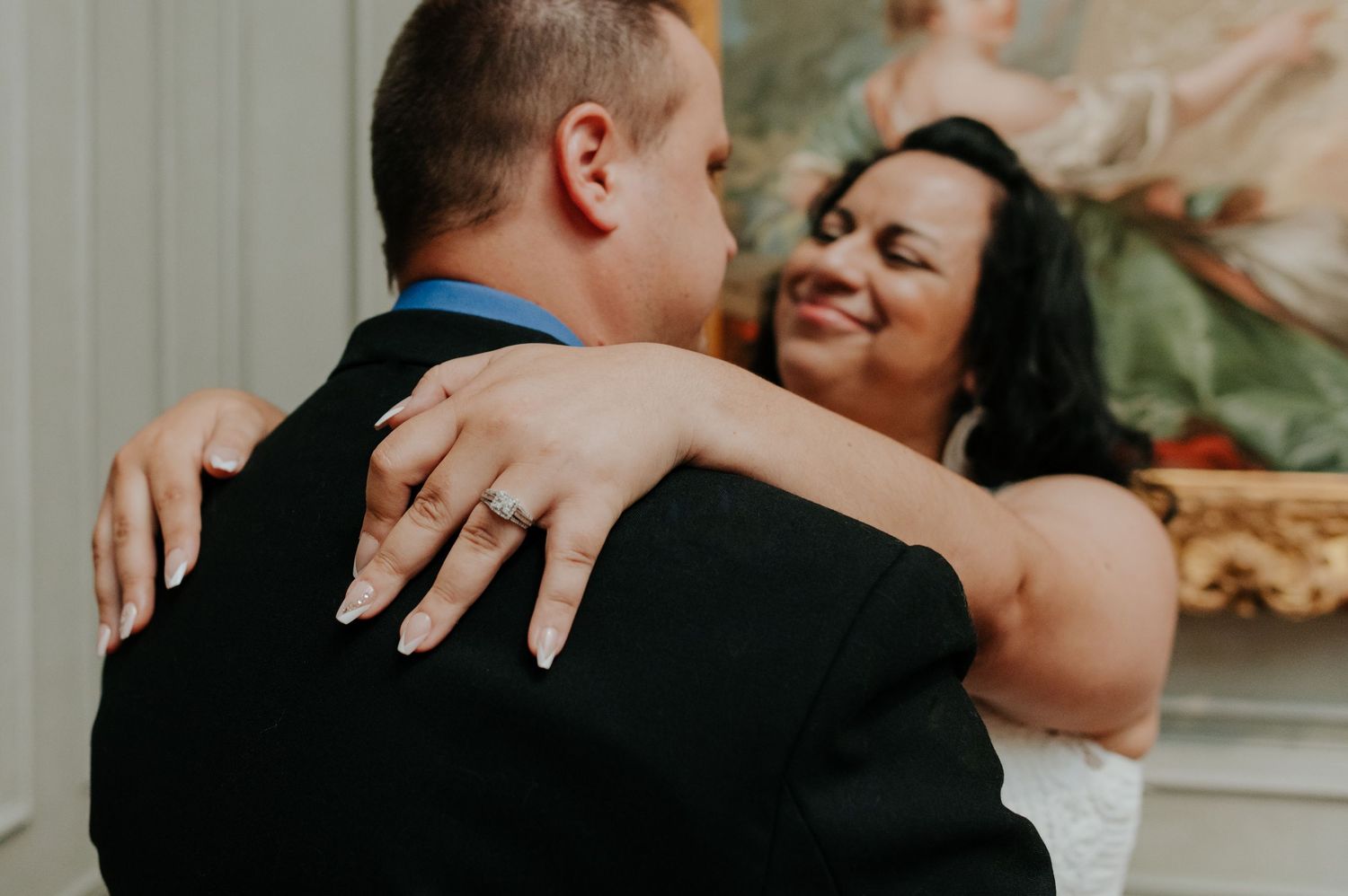 A joyful couple embraces during a romantic indoor wedding photoshoot with soft natural lighting.