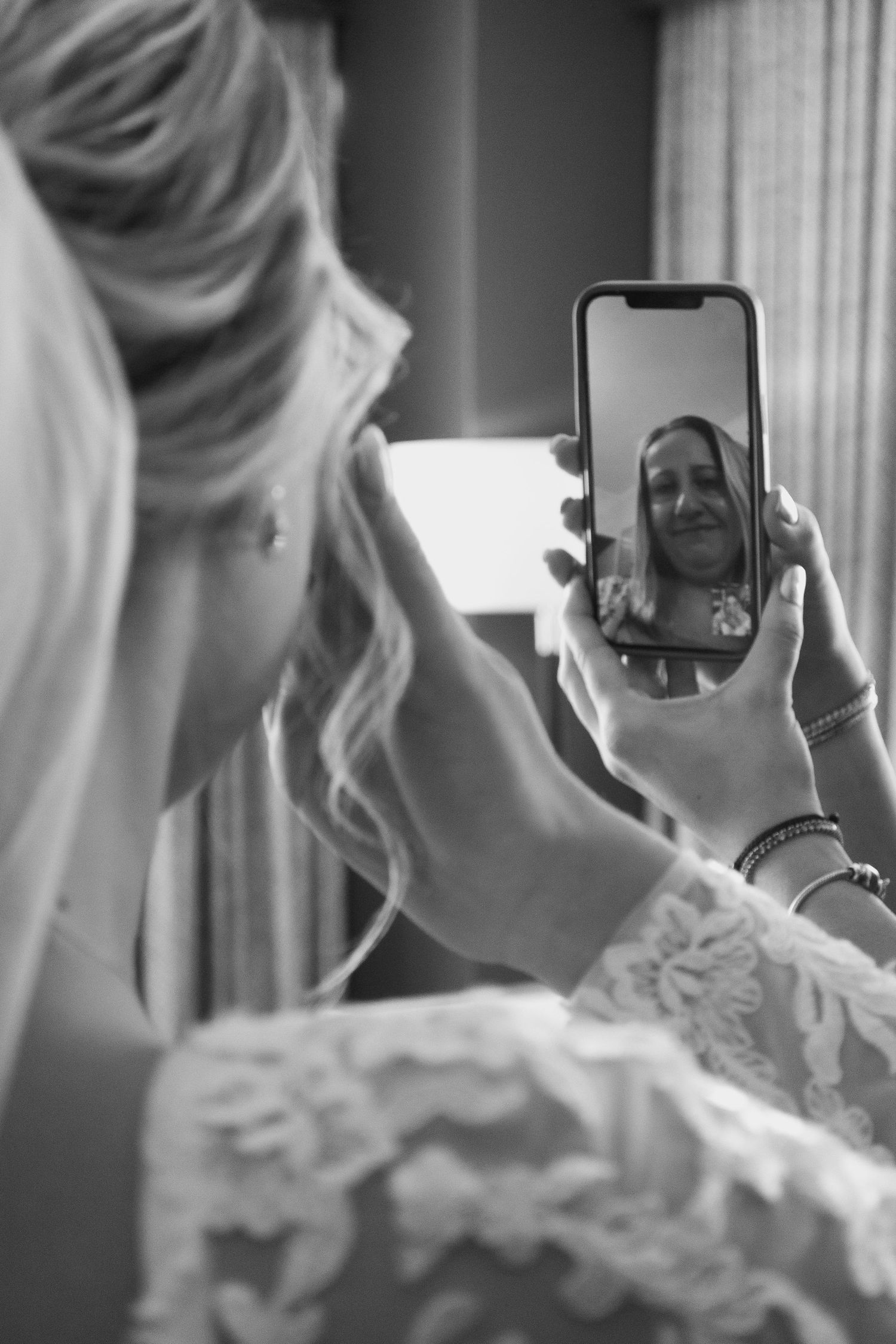 A sequence of black and white photos showing a bride having her veil adjusted in the mirror during wedding preparations.