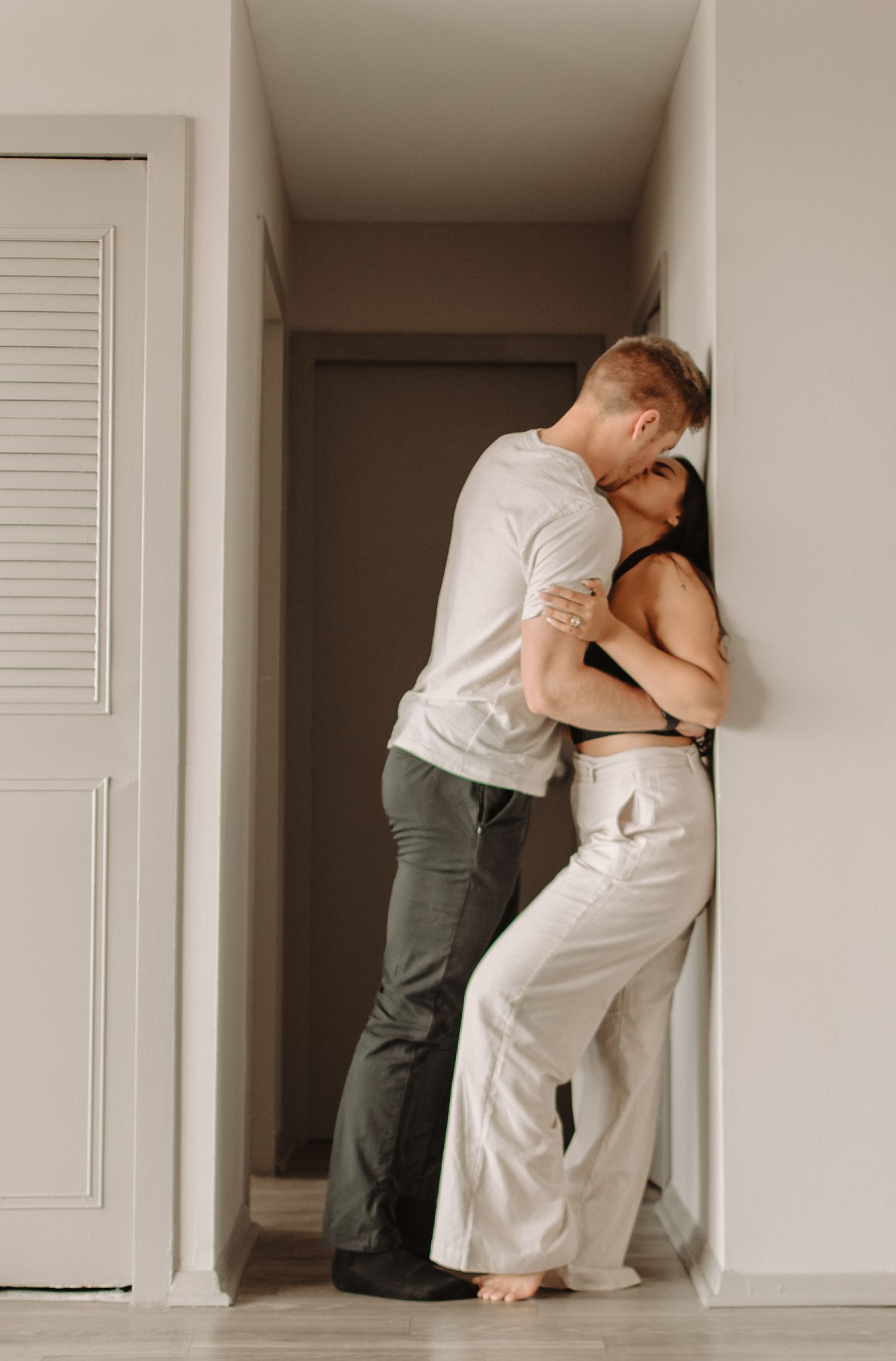 An intimate sequence of a couple embracing against a white wall in four similar poses with soft lighting and neutral tones.