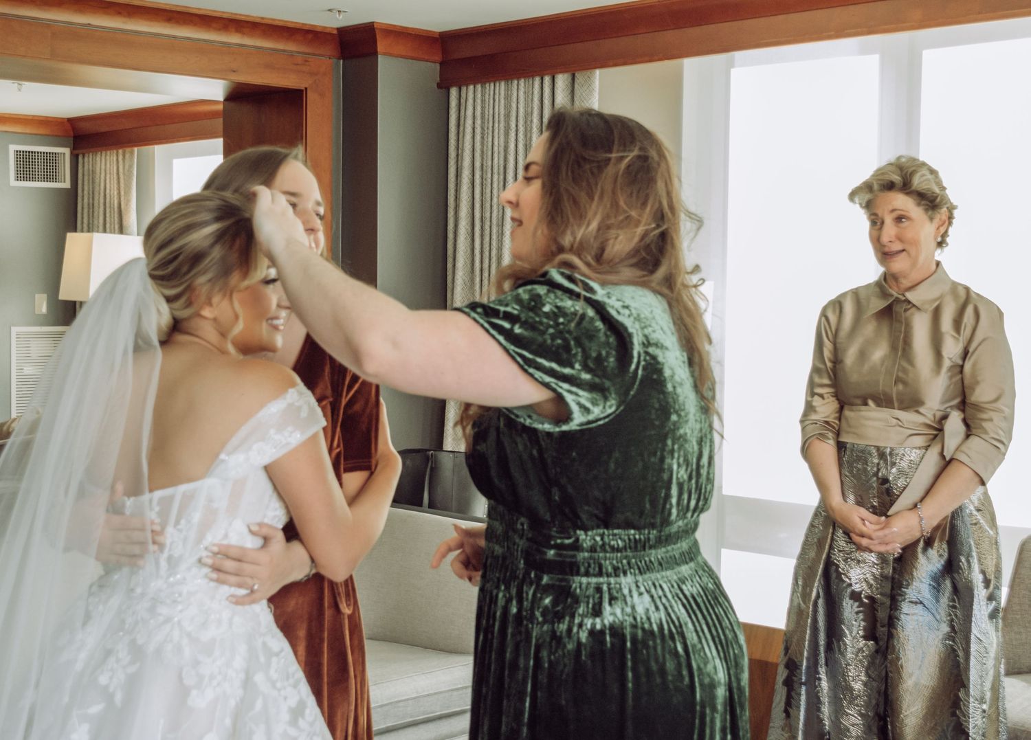 Final preparations being made to a bride's wedding dress and veil in a hotel room.