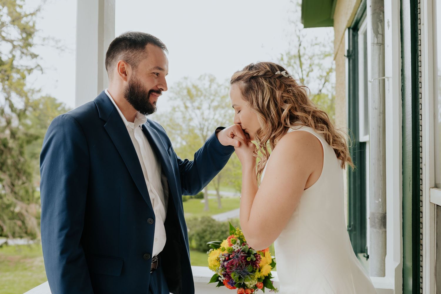 Couple sharing a joyful moment during outdoor wedding ceremony with colorful autumn bouquet.