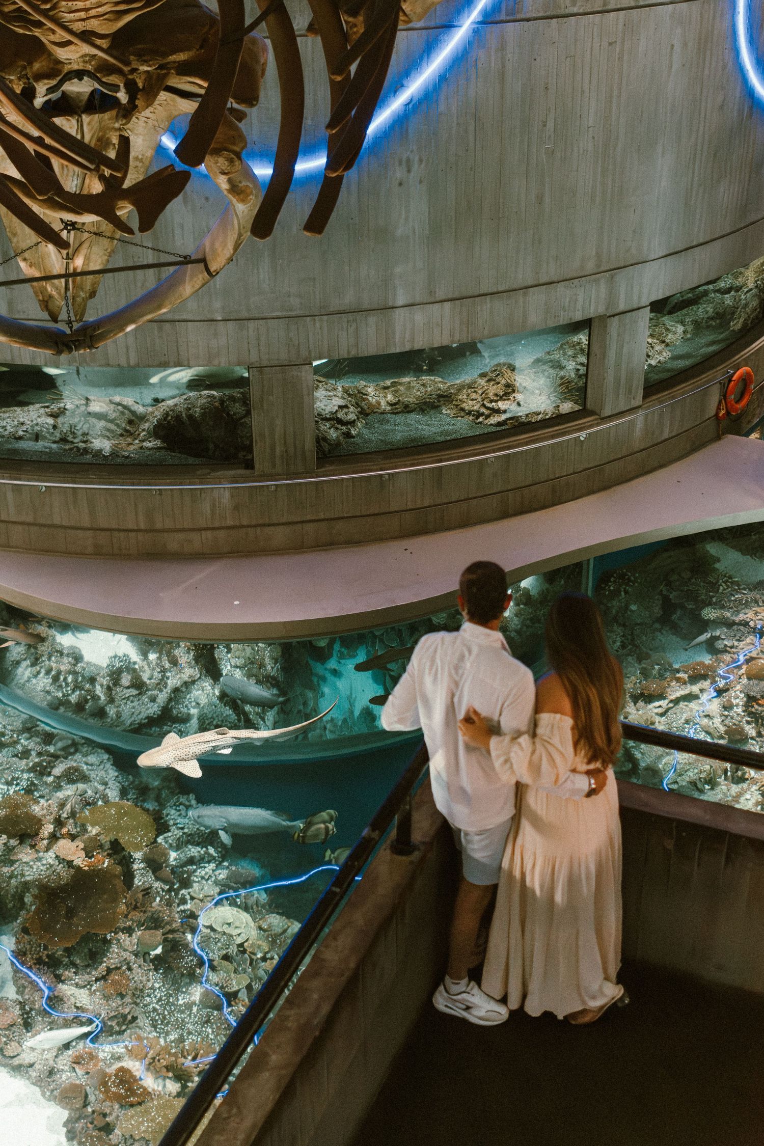 White clothing items hang suspended above a dark display area with glowing blue lighting and textured surfaces below.