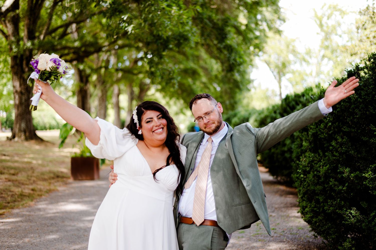 A couple shares a joyful dance moment together in a lush garden setting surrounded by greenery.