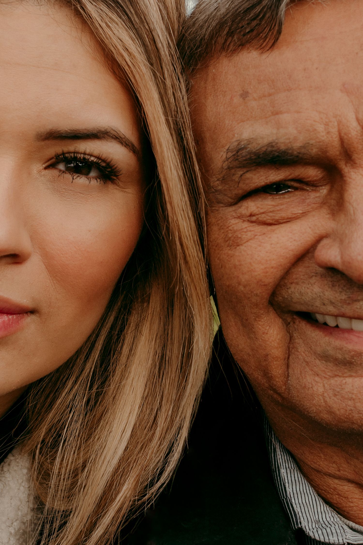 Close up view of an older man and younger woman smiling together in a warm, candid moment.